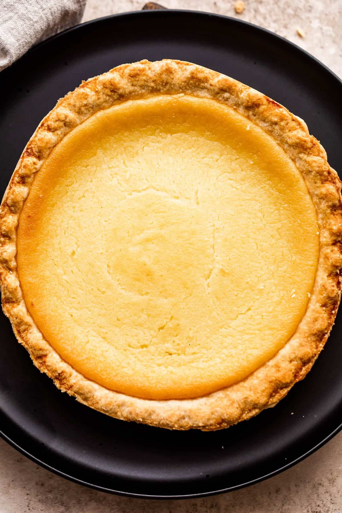 overhead shot of homemade buttermilk pie set on a black plate.