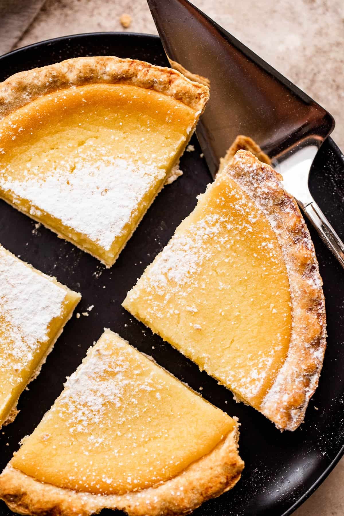 overhead shot of buttermilk pie cut into 4 slices and dusted with powdered sugar.