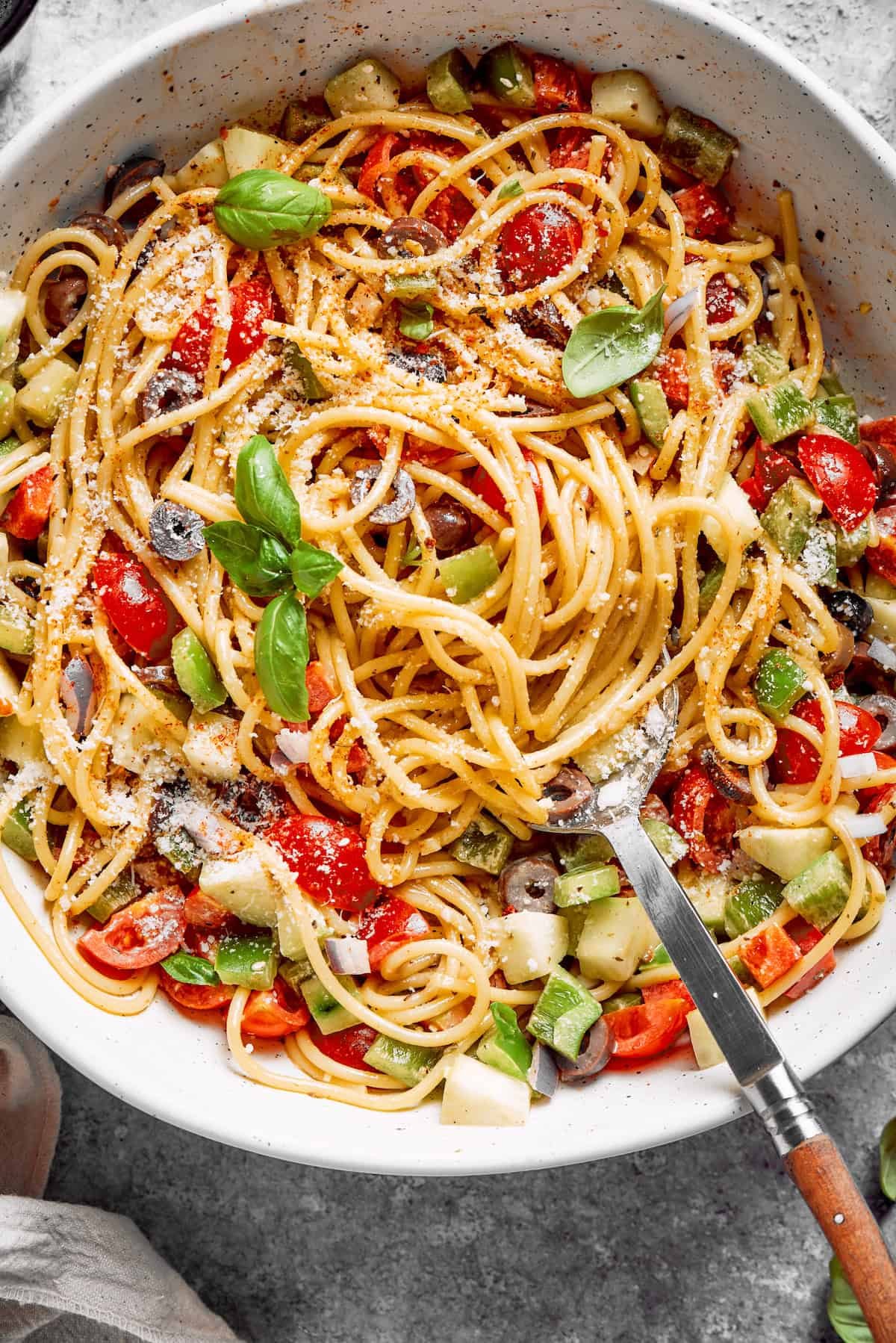 Fresh vegetables are shown in a bowl of spaghetti salad.