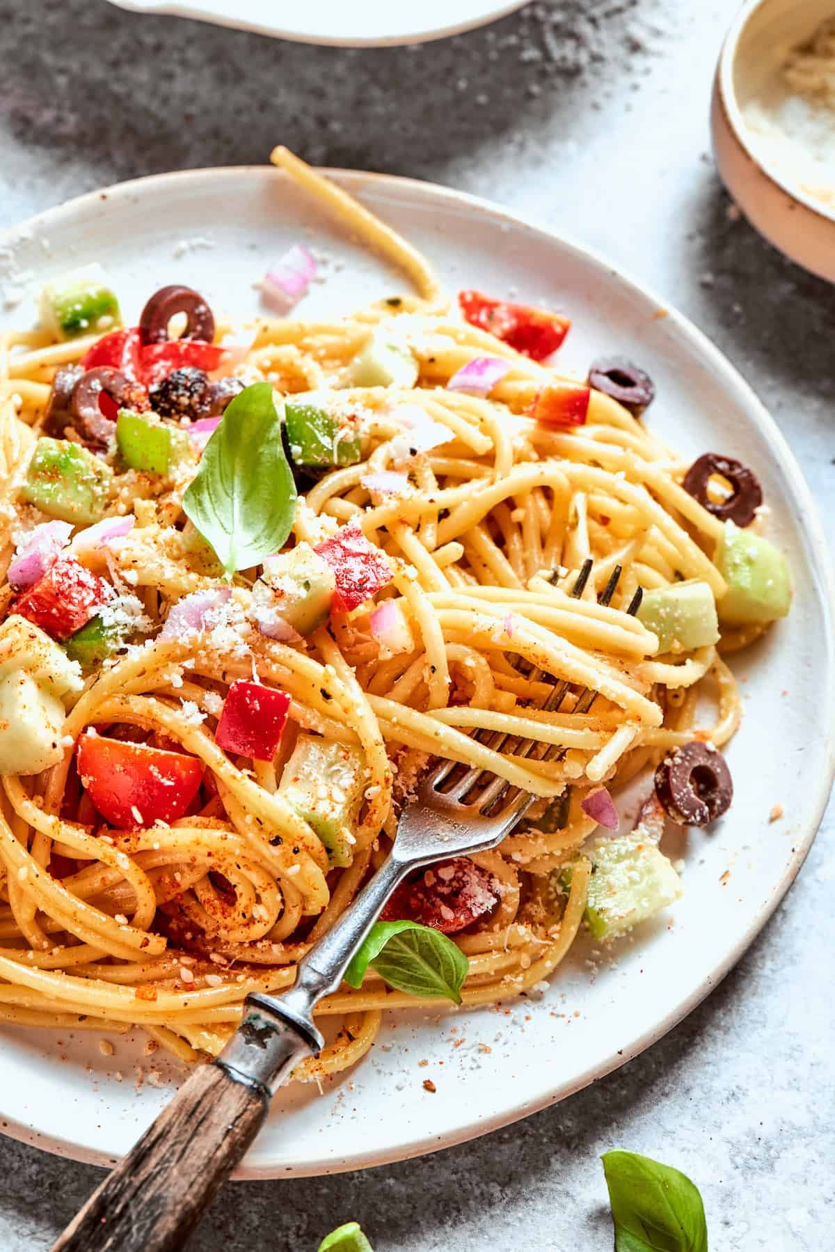 A fork scoops into a plate of spaghetti salad.