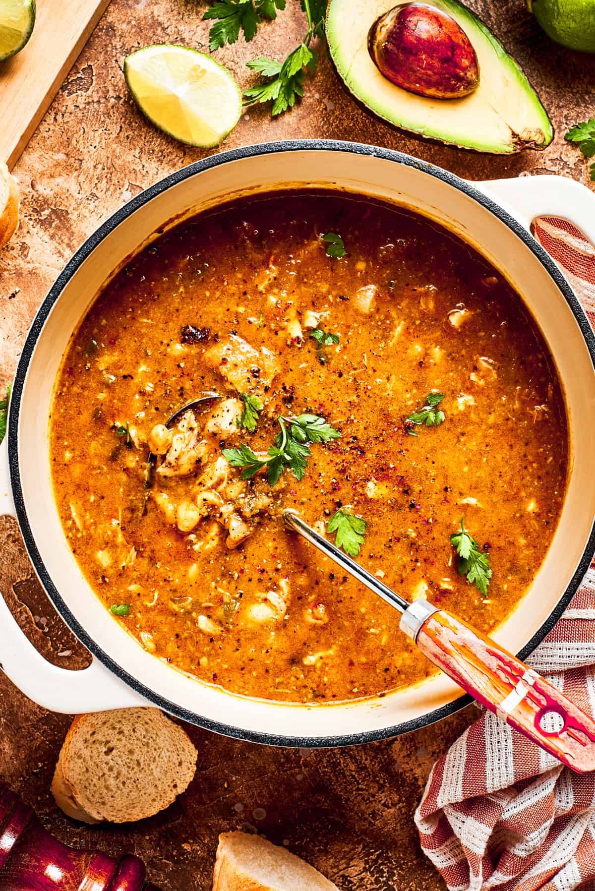 A pot of spicy chicken soup is mixed to combine all the ingredients.