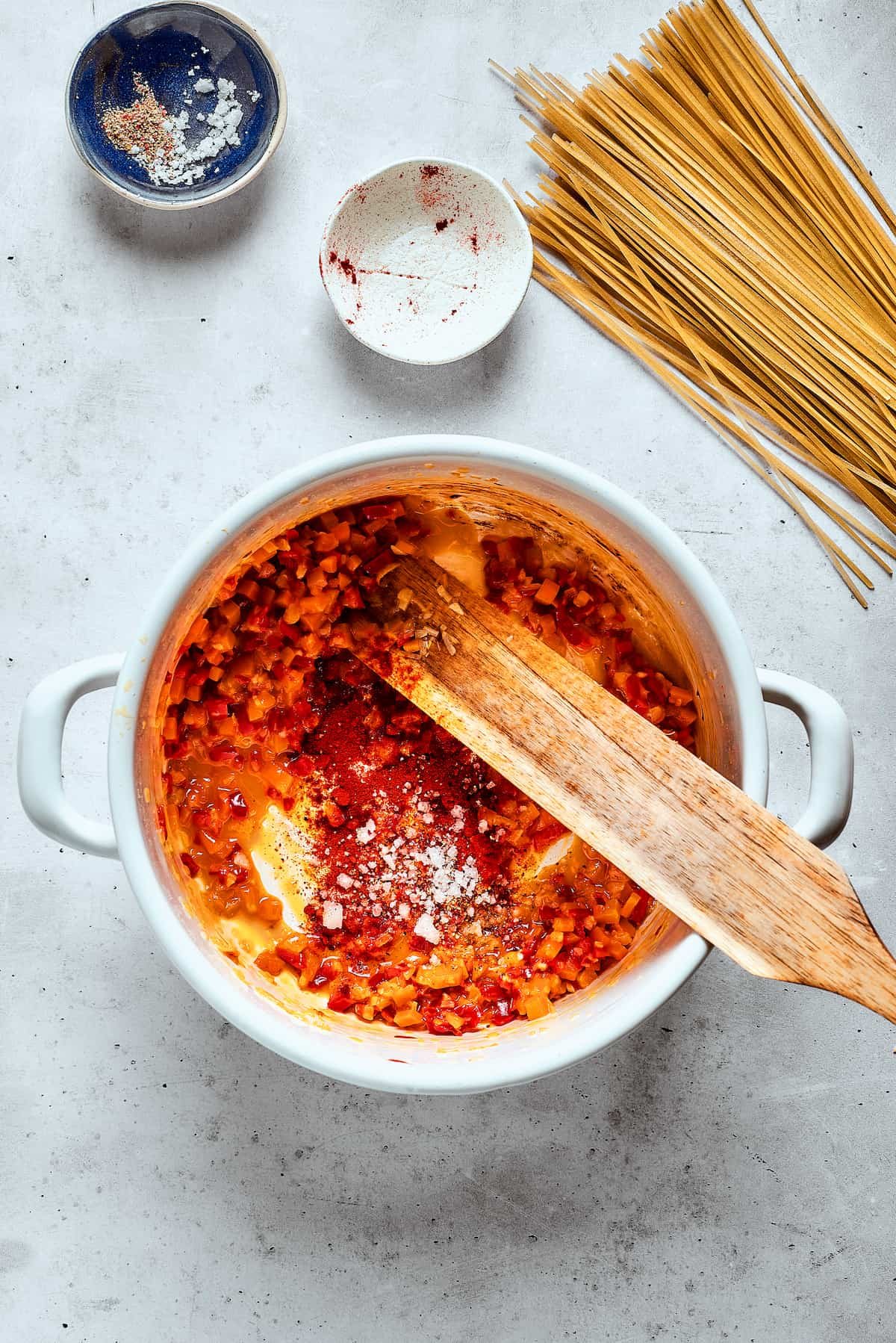 A wooden spoon stirs cooking vegetables in the soup pot.