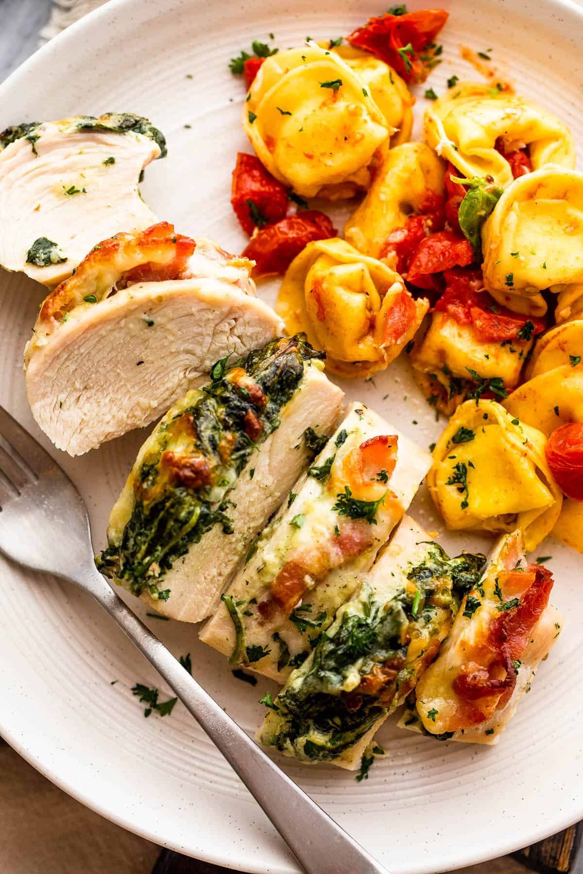 cut up stuffed chicken breast served alongside tortellini pasta