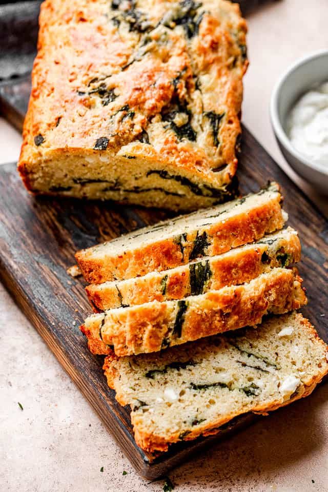 top shot of sliced spinach and feta bread set on top of a dark cutting board