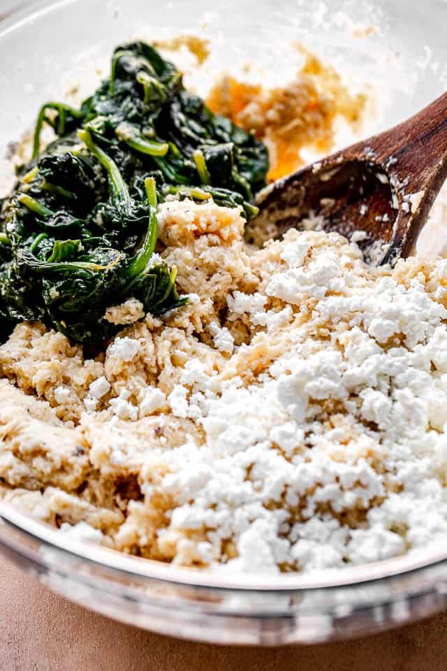 side view of a mixing bowl with spinach, cheese, and flour