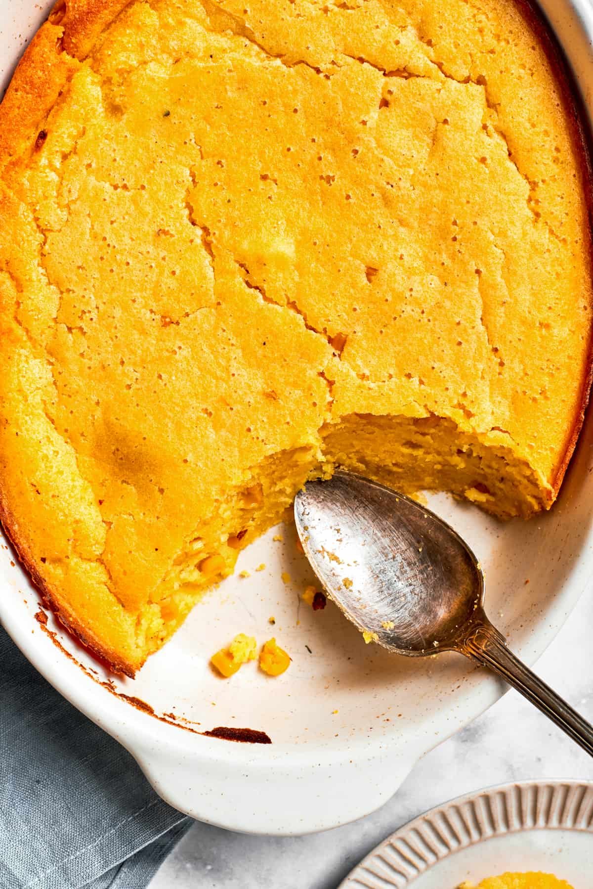 Serving spoon resting next to a baked bread in a casserole dish.