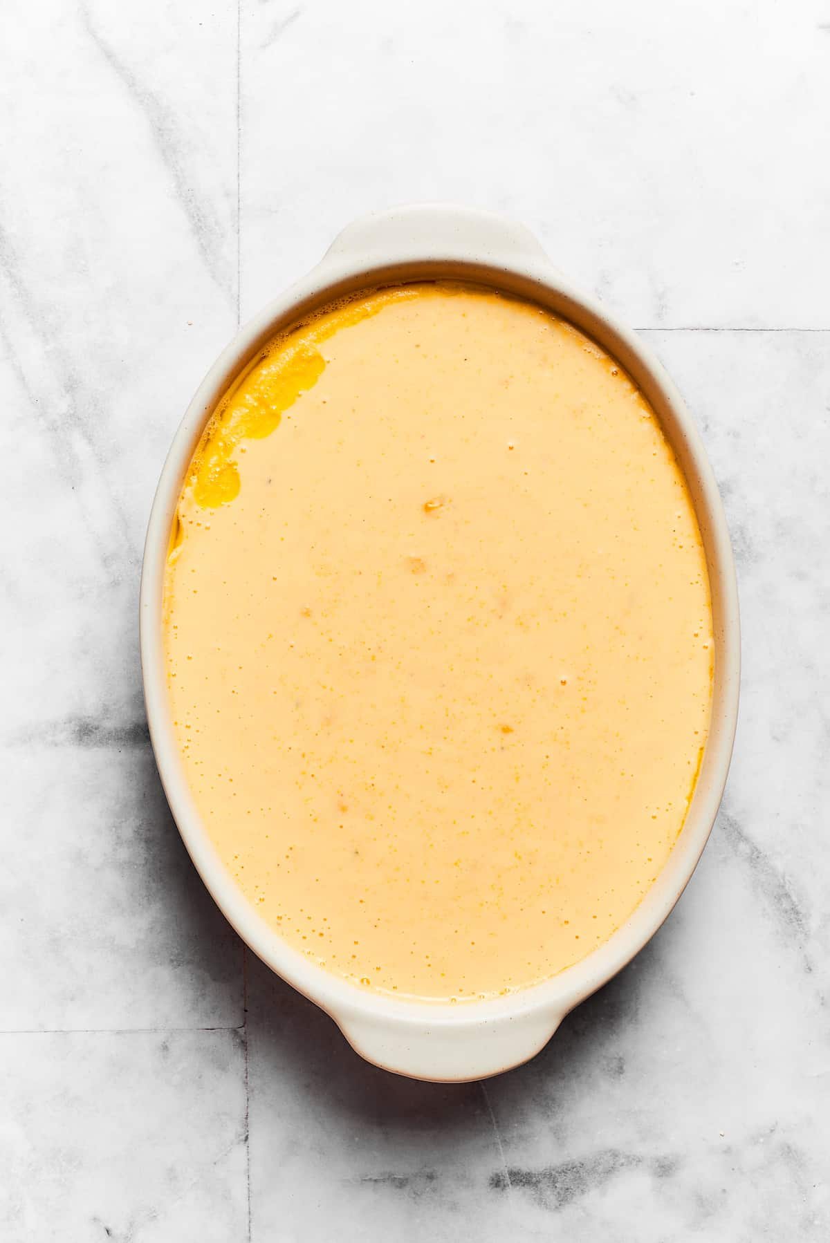 Spoon bread batter is shown in an oval baking dish.