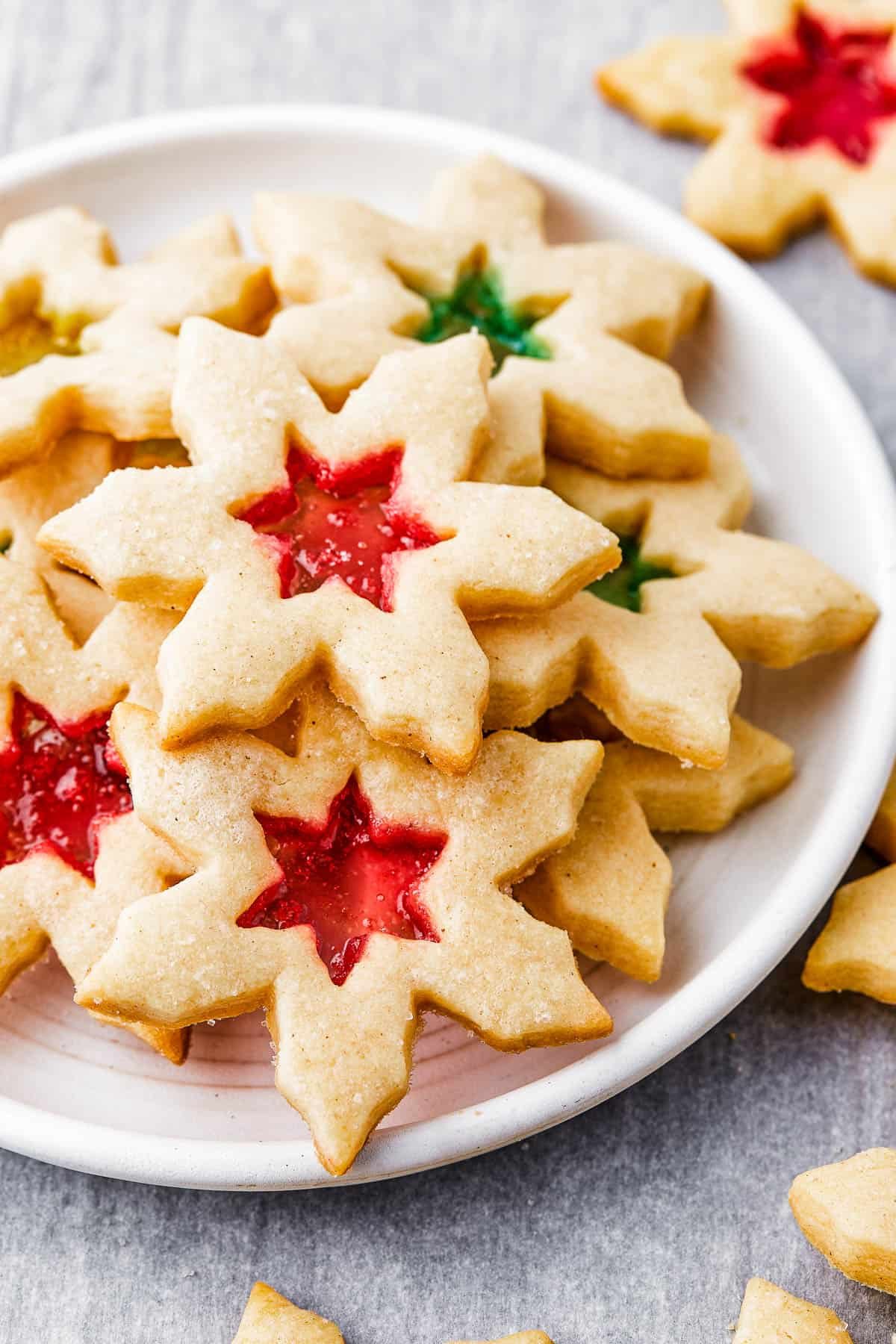 Snowflake-shaped sugar cookies with red and green centers on a round white plate.