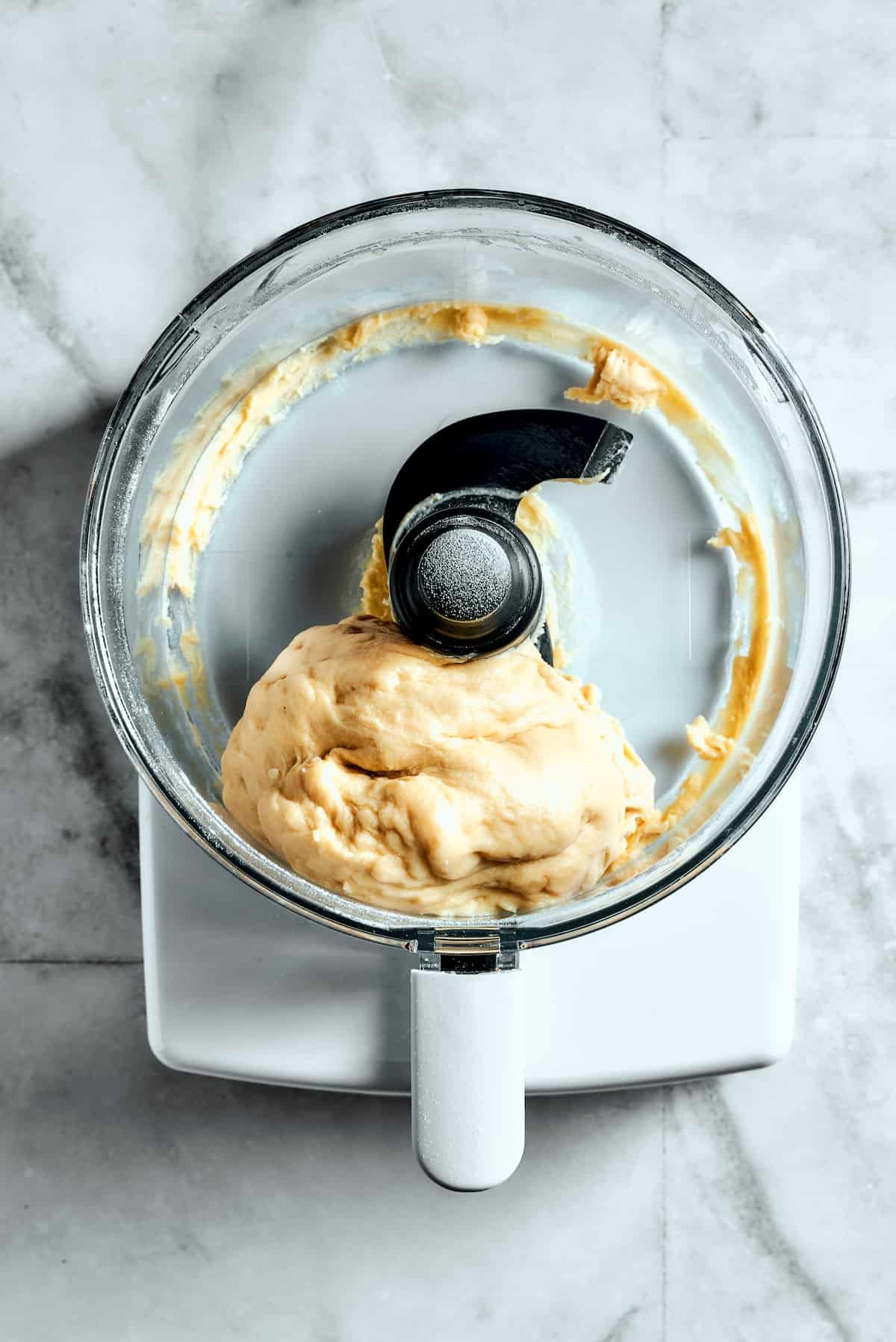 Overhead view of dough in a food processor.
