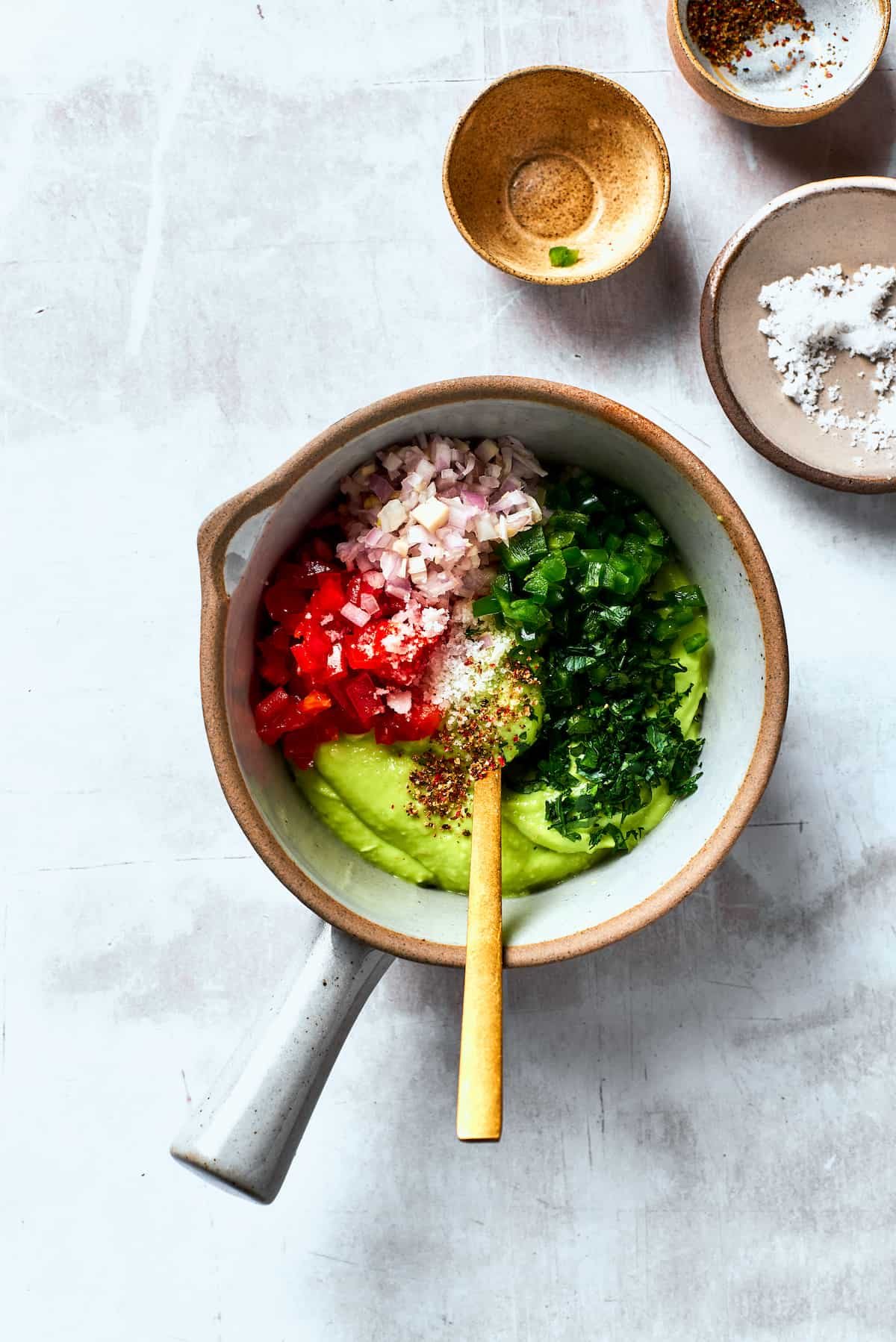 Onions, cilantro, and tomatoes are stirred into a bowl guacamole.