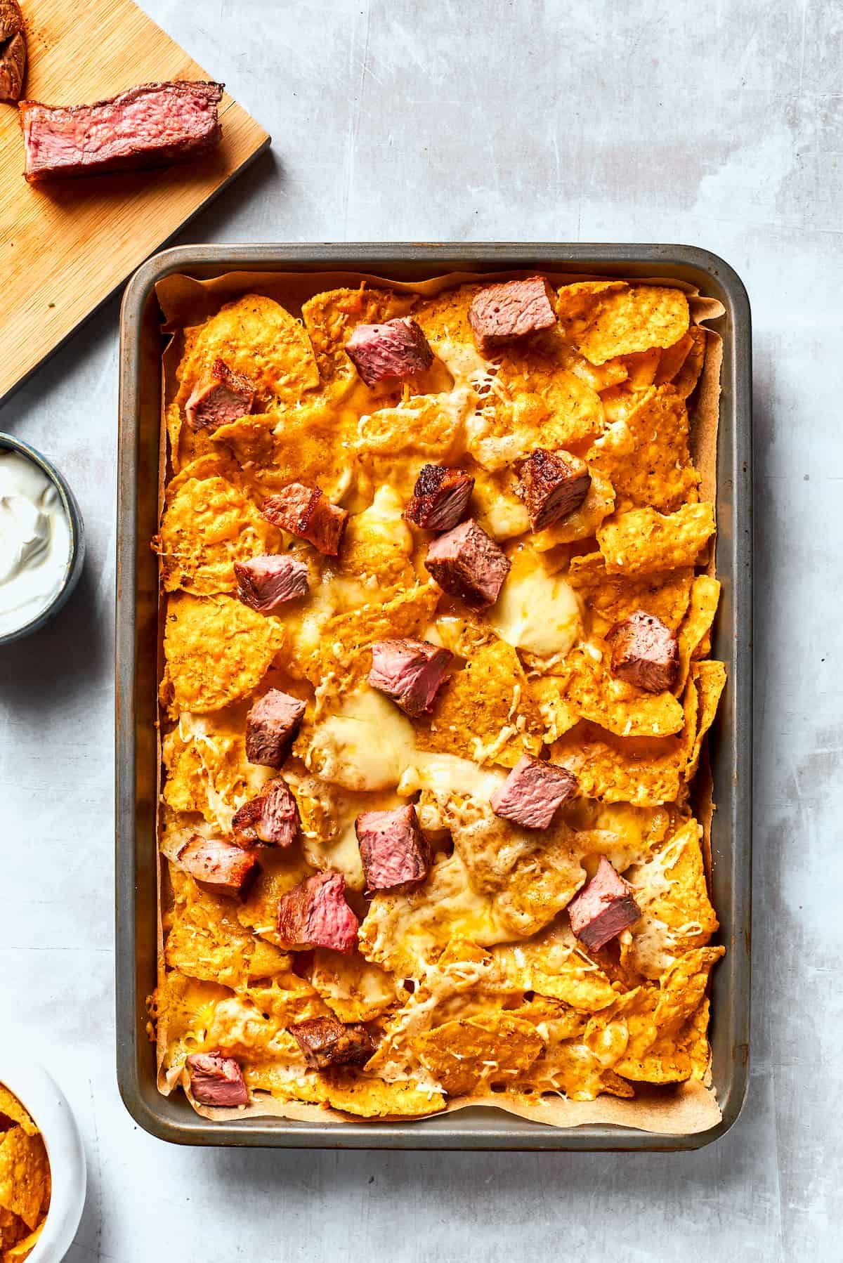 A pan of tortilla chips topped with steak and cheese.