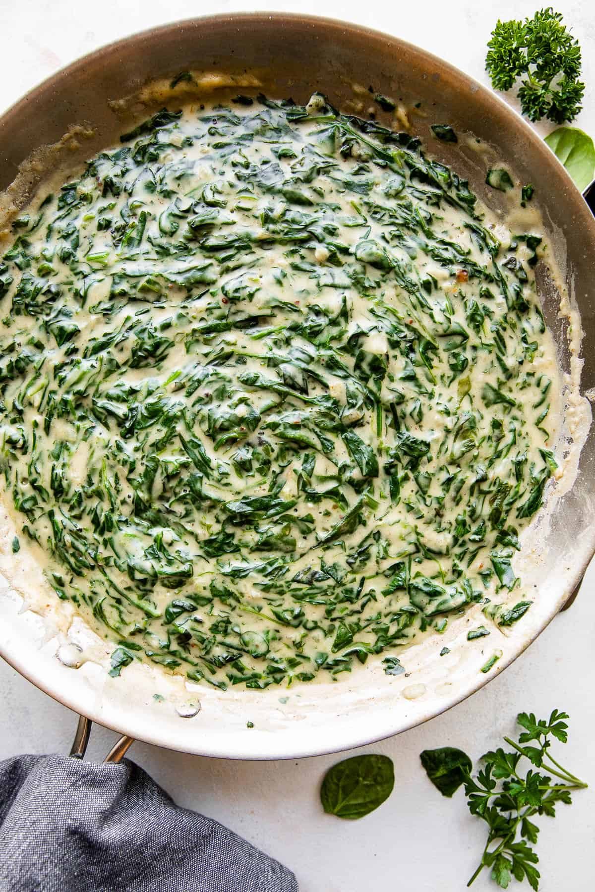 overhead picture of creamed spinach cooking in a large skillet.
