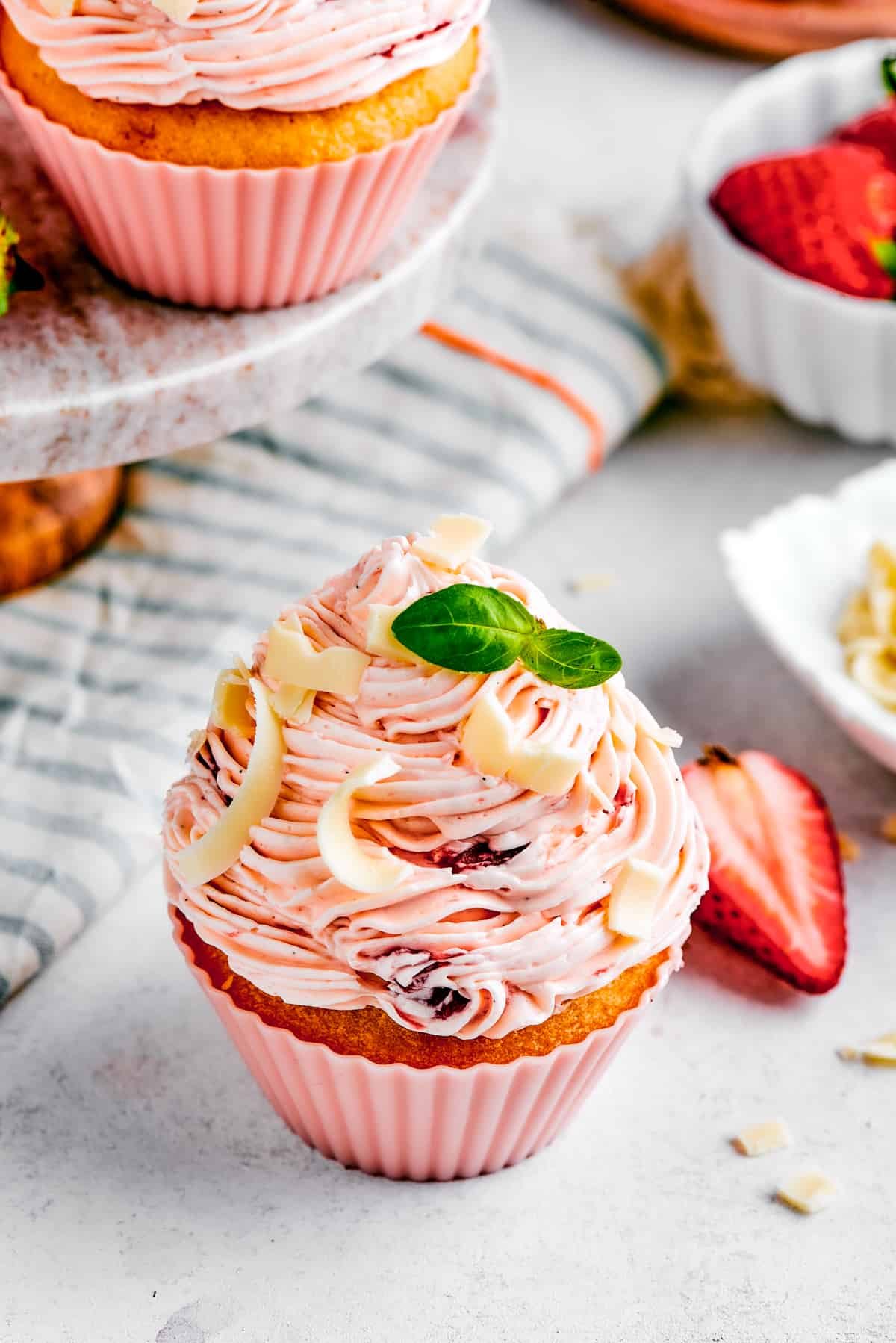 Overhead shot of a cupcake next to an unwrapped cupcake liner and half a strawberry.