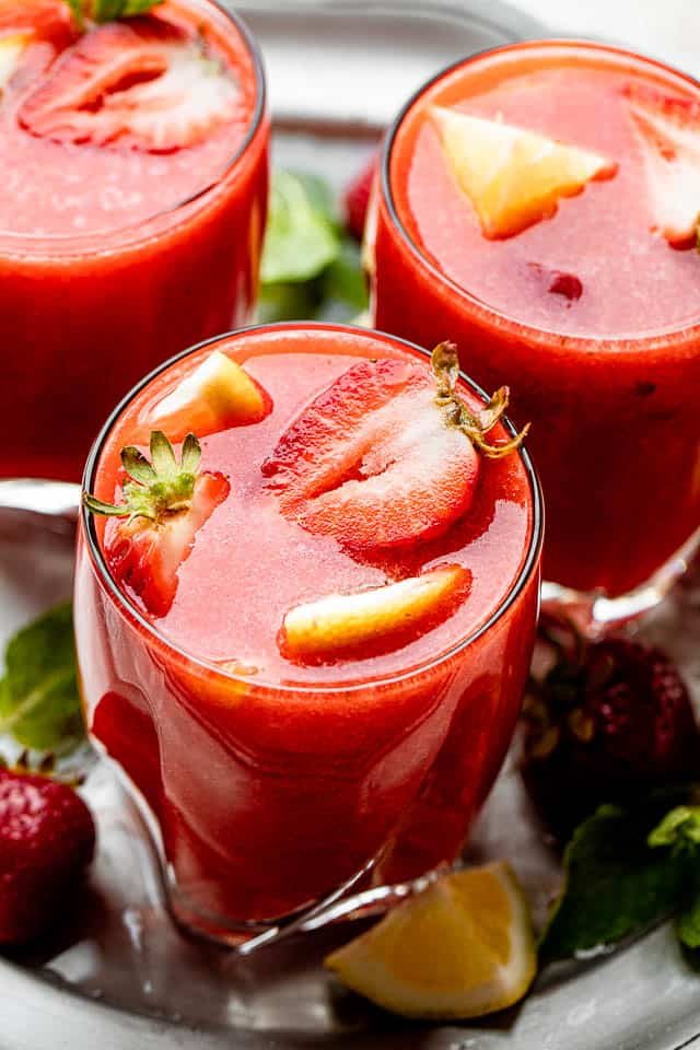strawberry sangria in short drinking glasses topped with strawberry slices and lemons