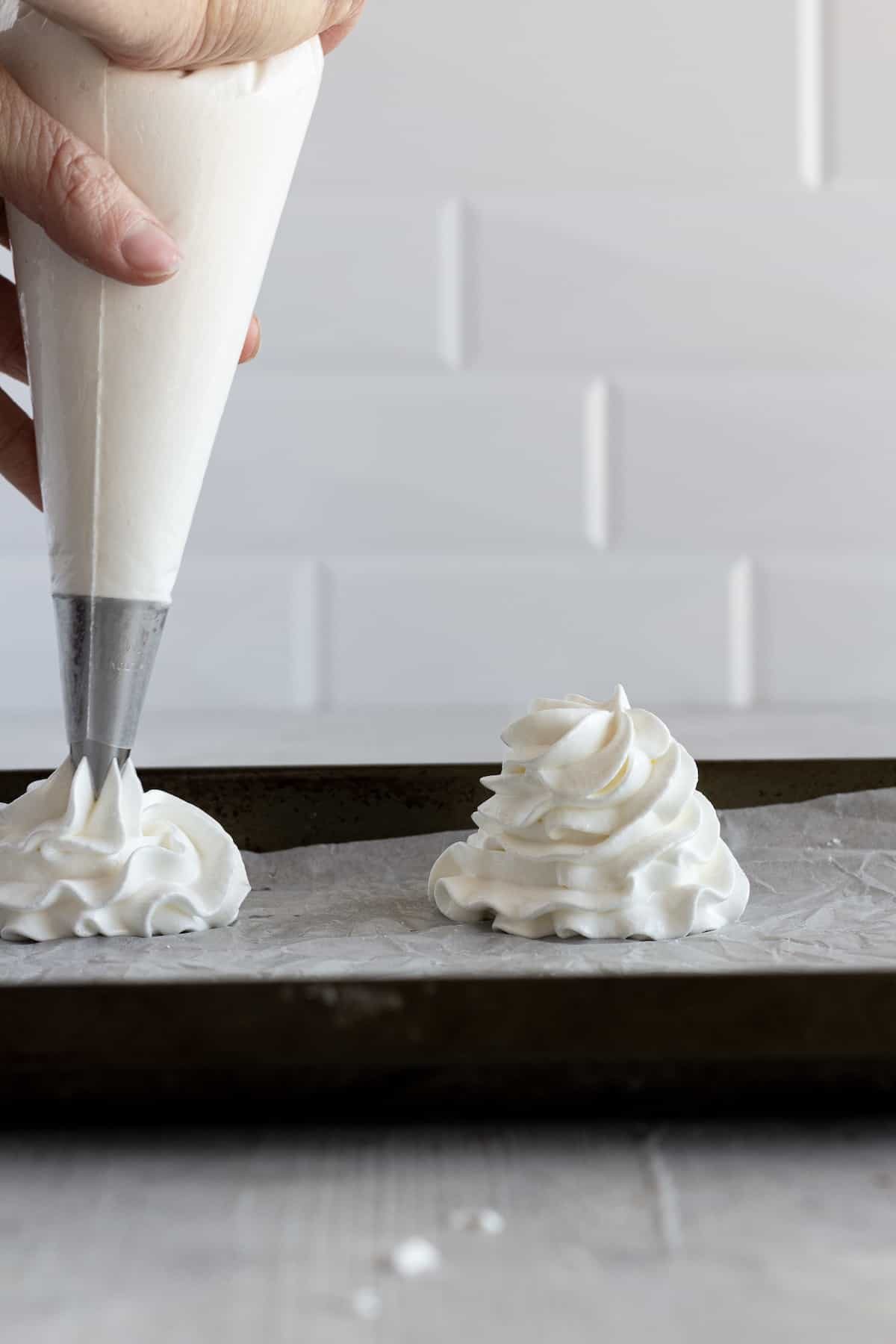 Piping bag pipping pavlova nests onto a baking sheet
