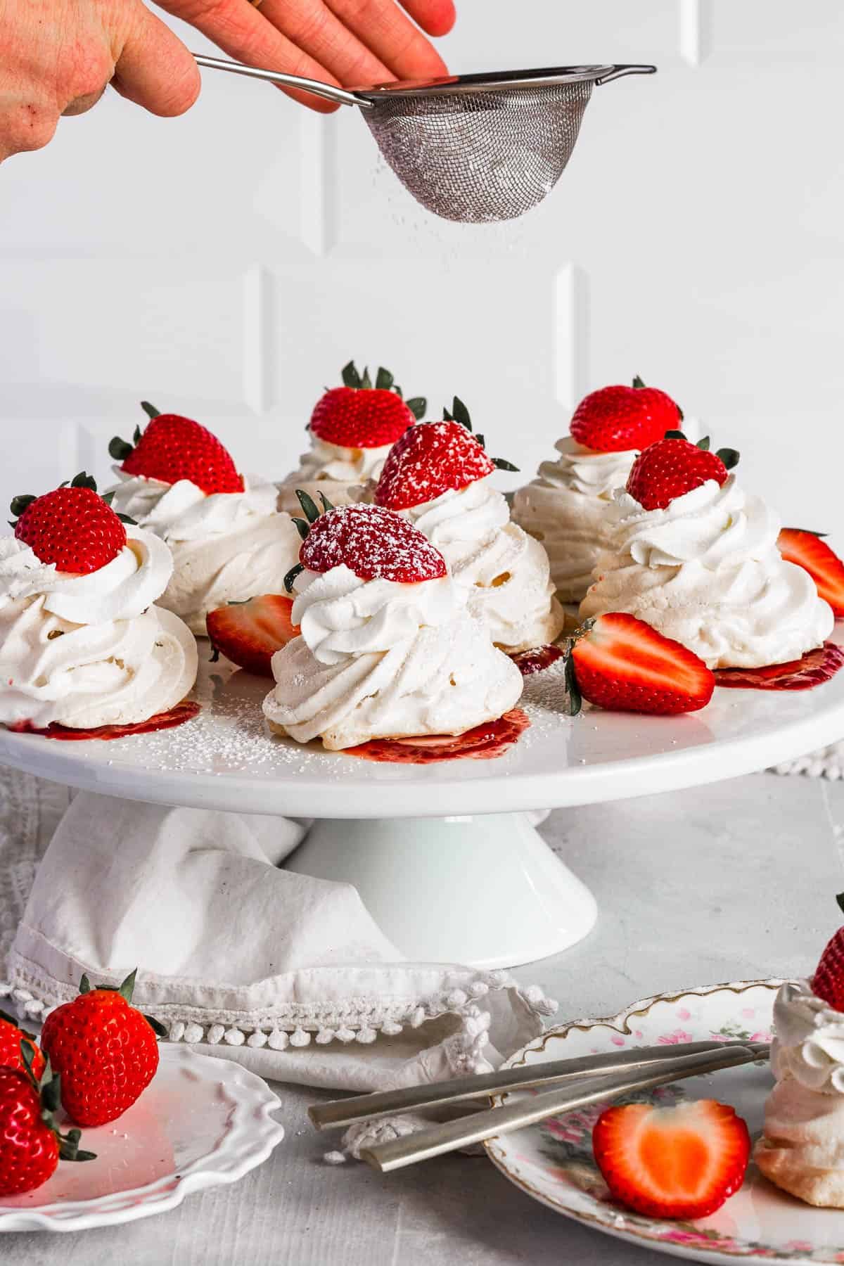 Sifting confectioners sugar onto pavlovas