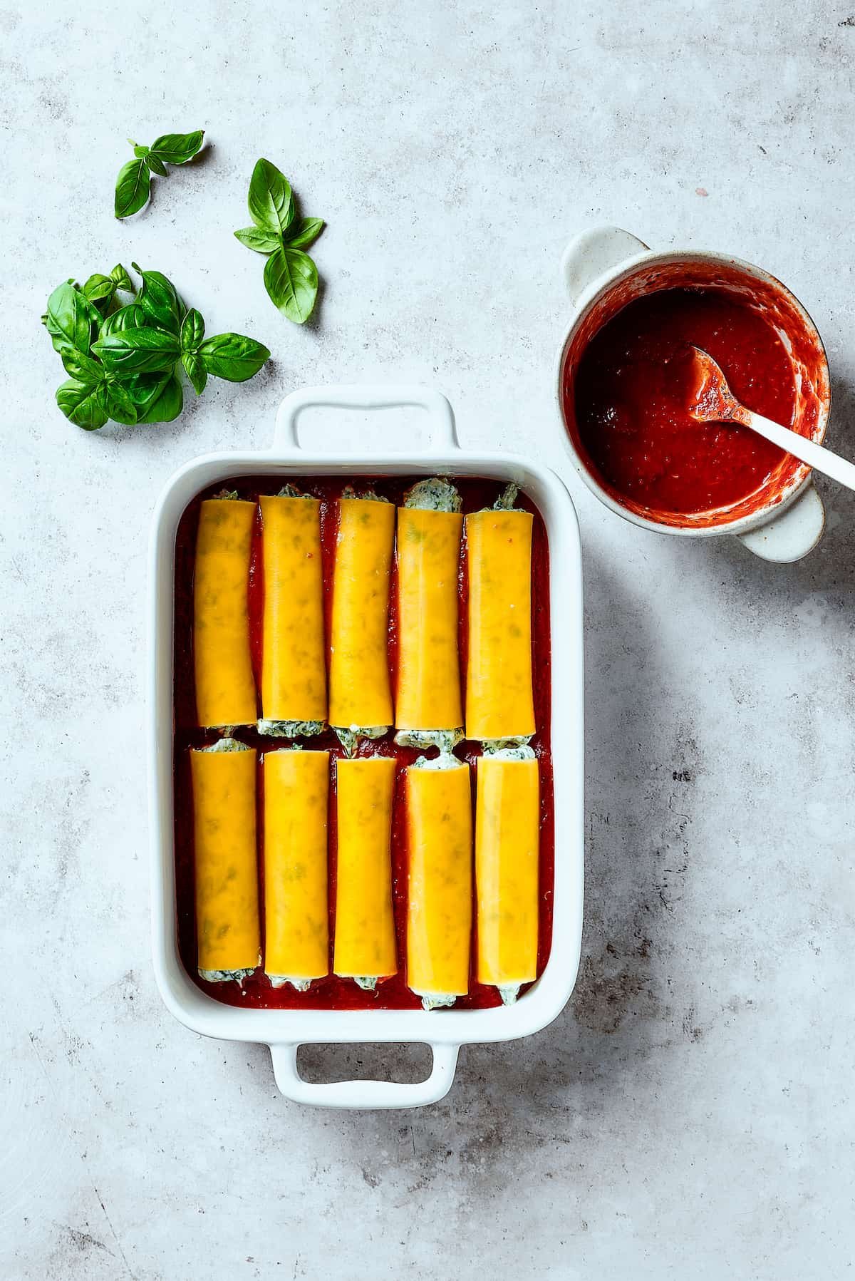 Stuffed manicotti pasta laid in a baking dish.