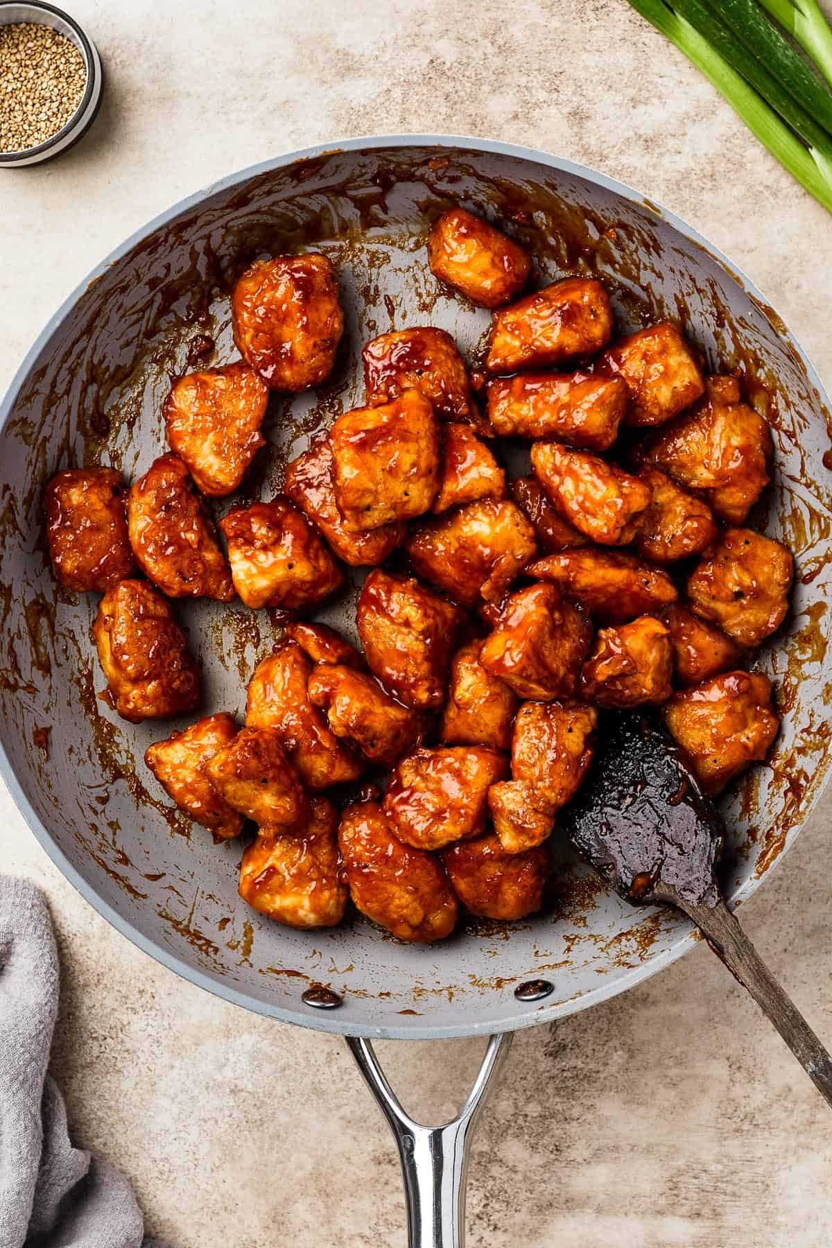 A skillet full of fried chicken in sweet and sour sauce.