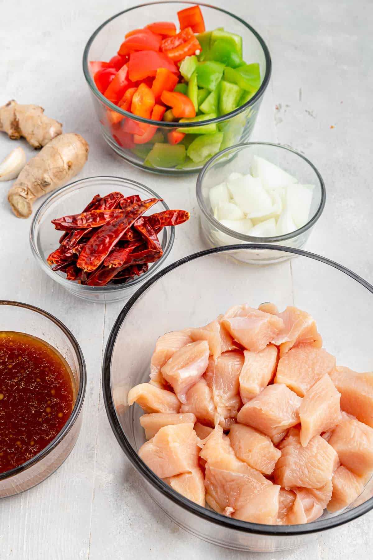 Clockwise from top: chopped bell pepper, chopped onion, cubed chicken, Szechuan sauce, dried chilies, ginger, garlic.