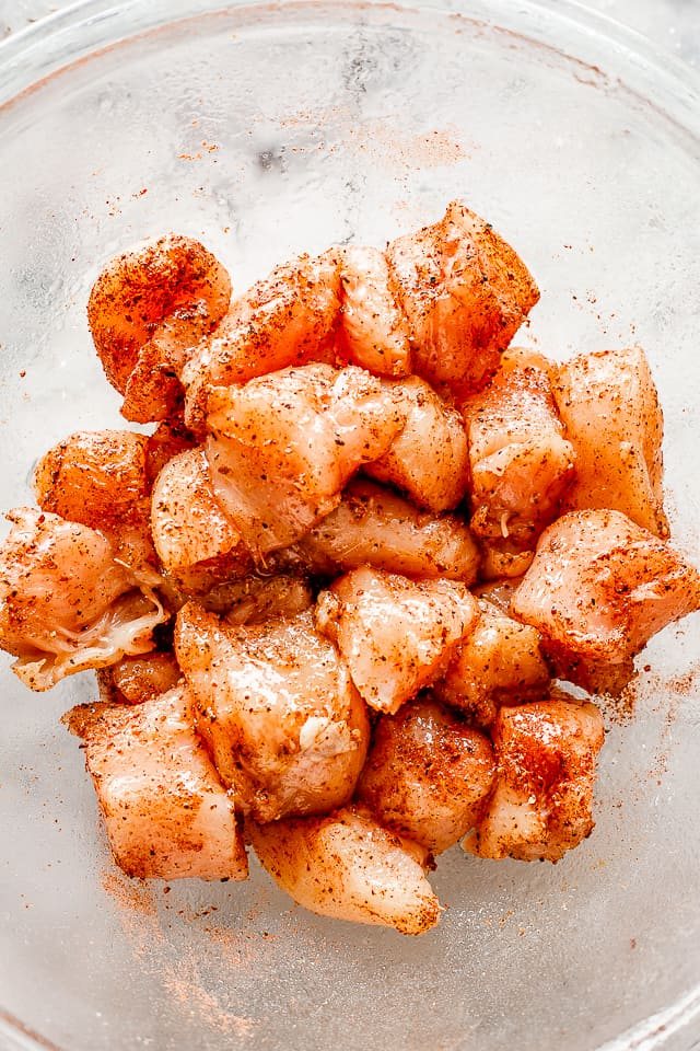 Raw cubes of chicken breast seasoned with taco seasoning.
