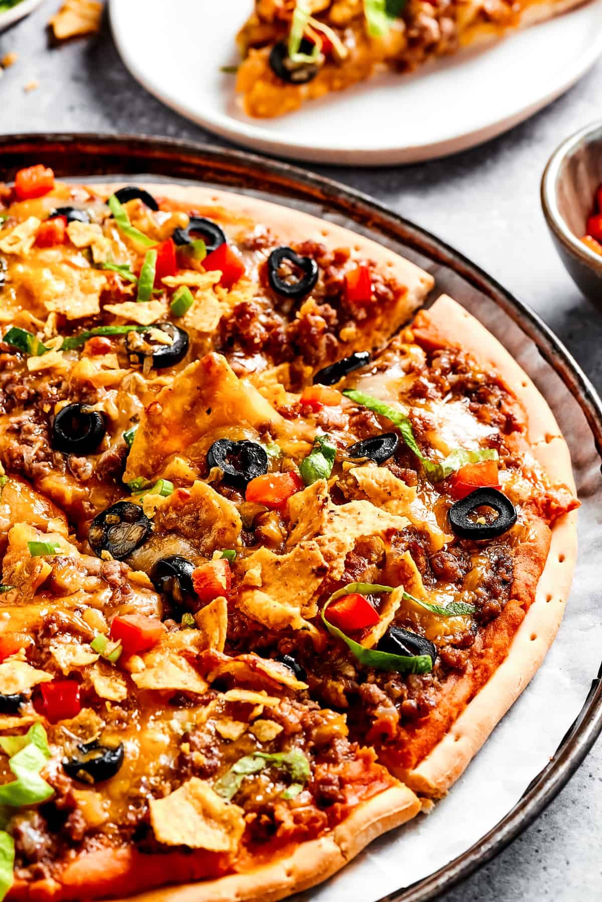 Homemade Mexican pizza with shredded lettuce, crushed tortilla chips, and other toppings.