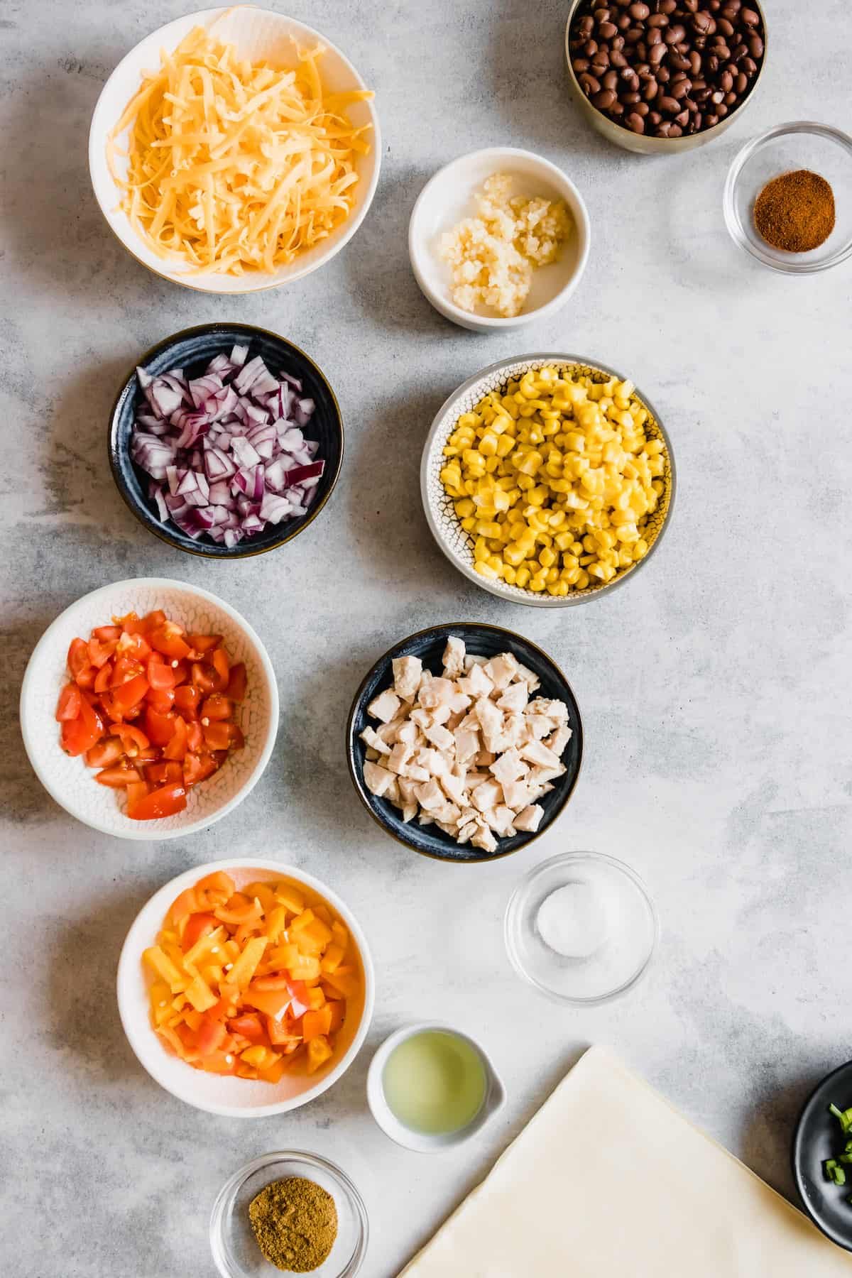 Shredded Cheese, Diced Tomatoes, Diced Chicken and the Rest of the Egg Roll Ingredients on a Countertop