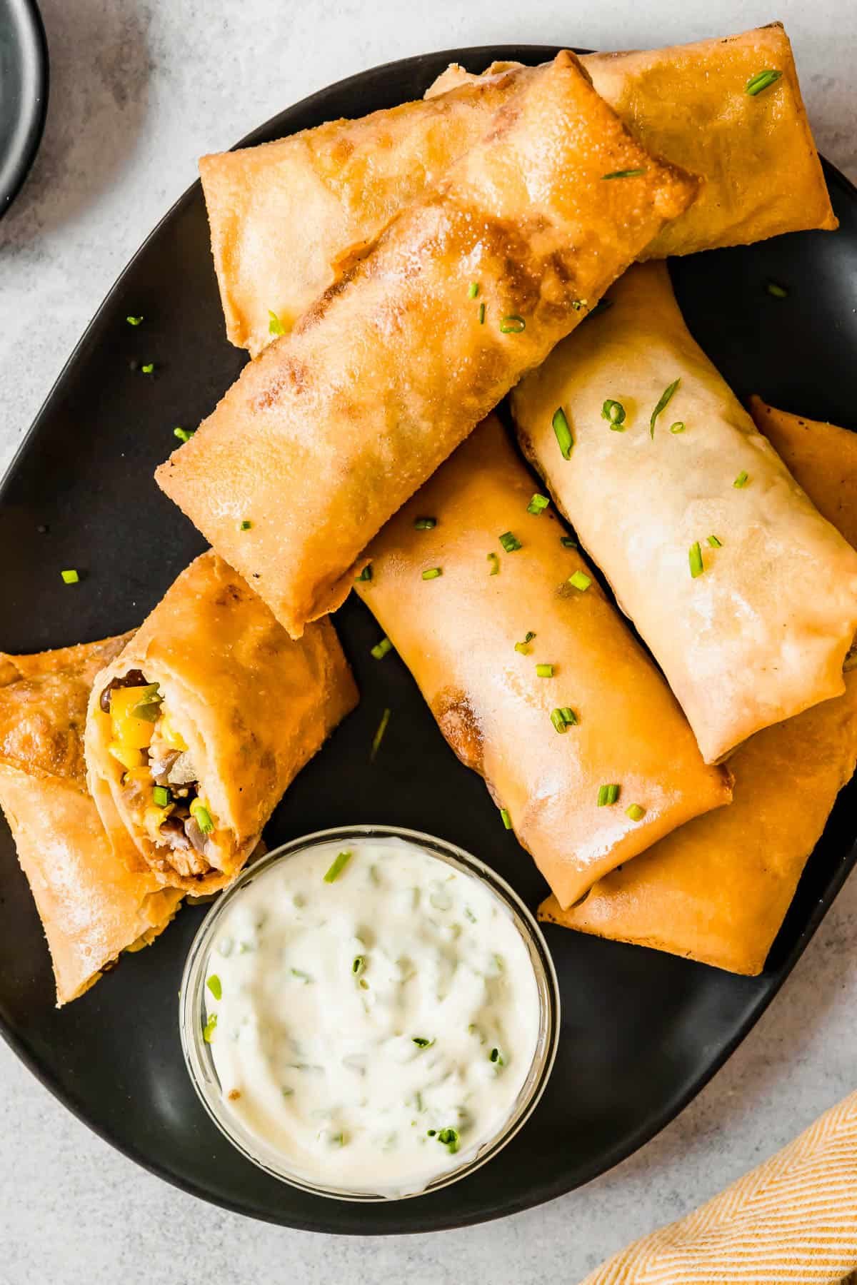 A Plate of Egg Rolls with a Glass Dish of Dipping Sauce