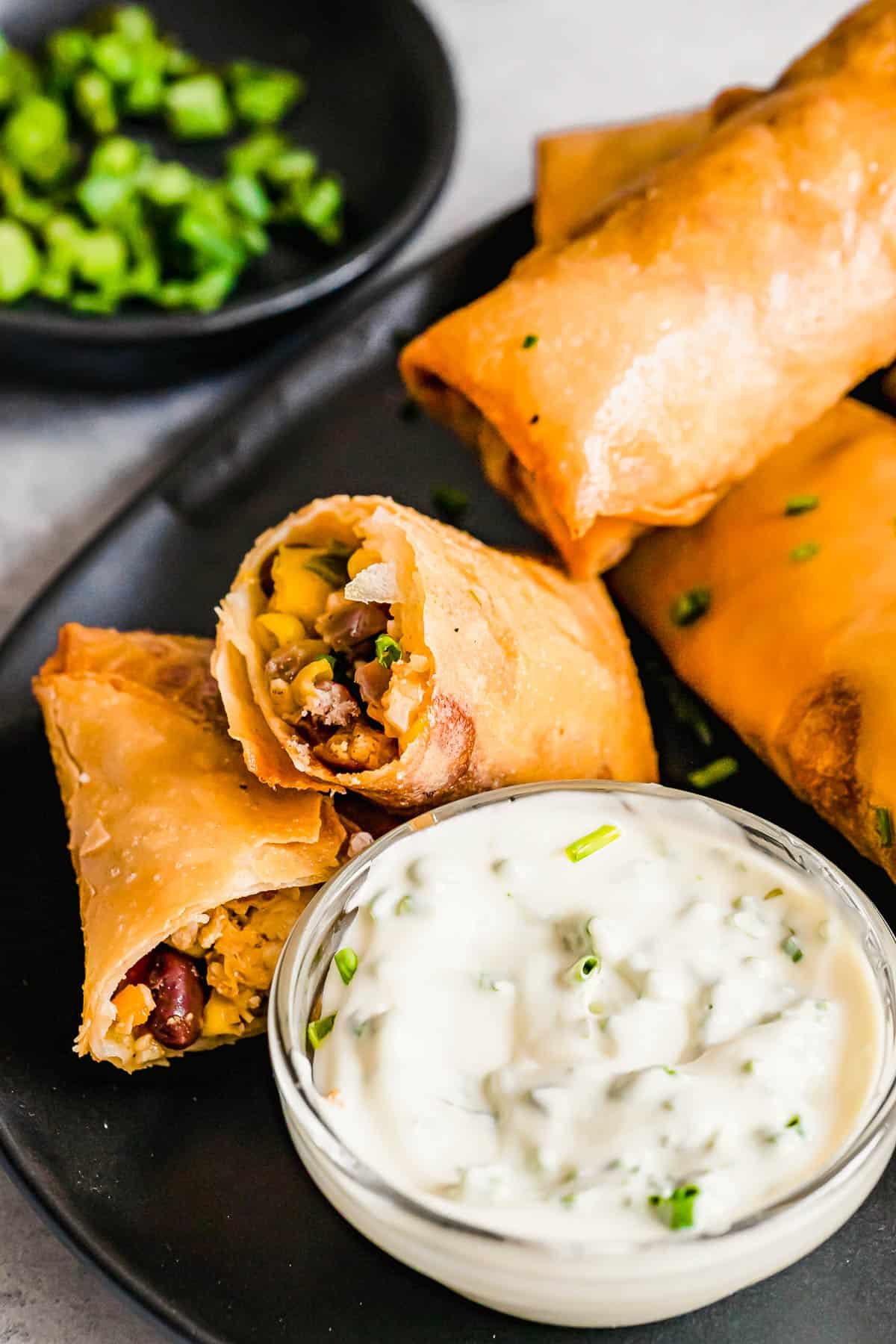 A Plate of Egg Rolls with a Glass Dish of Dipping Sauce