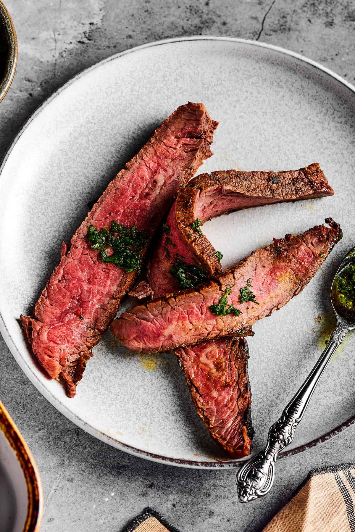 Medium-rare steak slices on a small plate, drizzled with sauce.