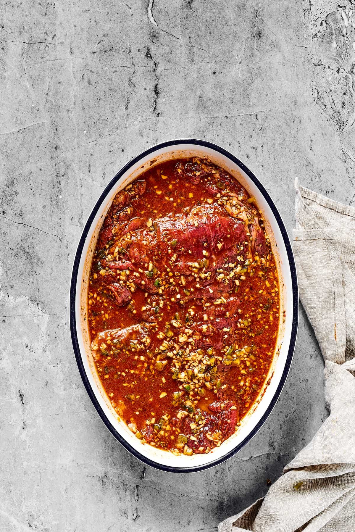 Flank steak fully covered by a marinade with garlic and jalpano.