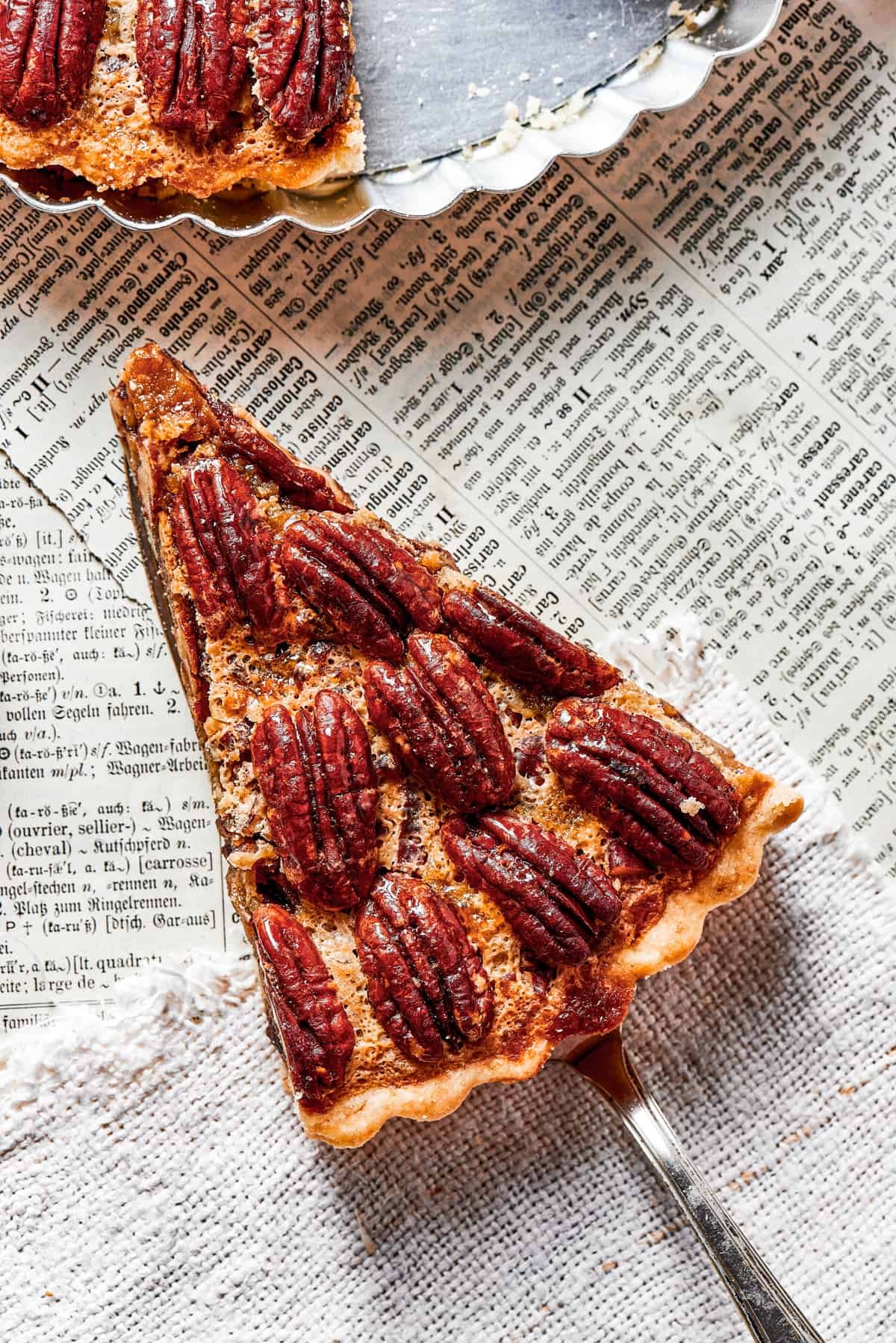overhead shot of a slice of pie held over a newspaper, and a pie plate placed above it.