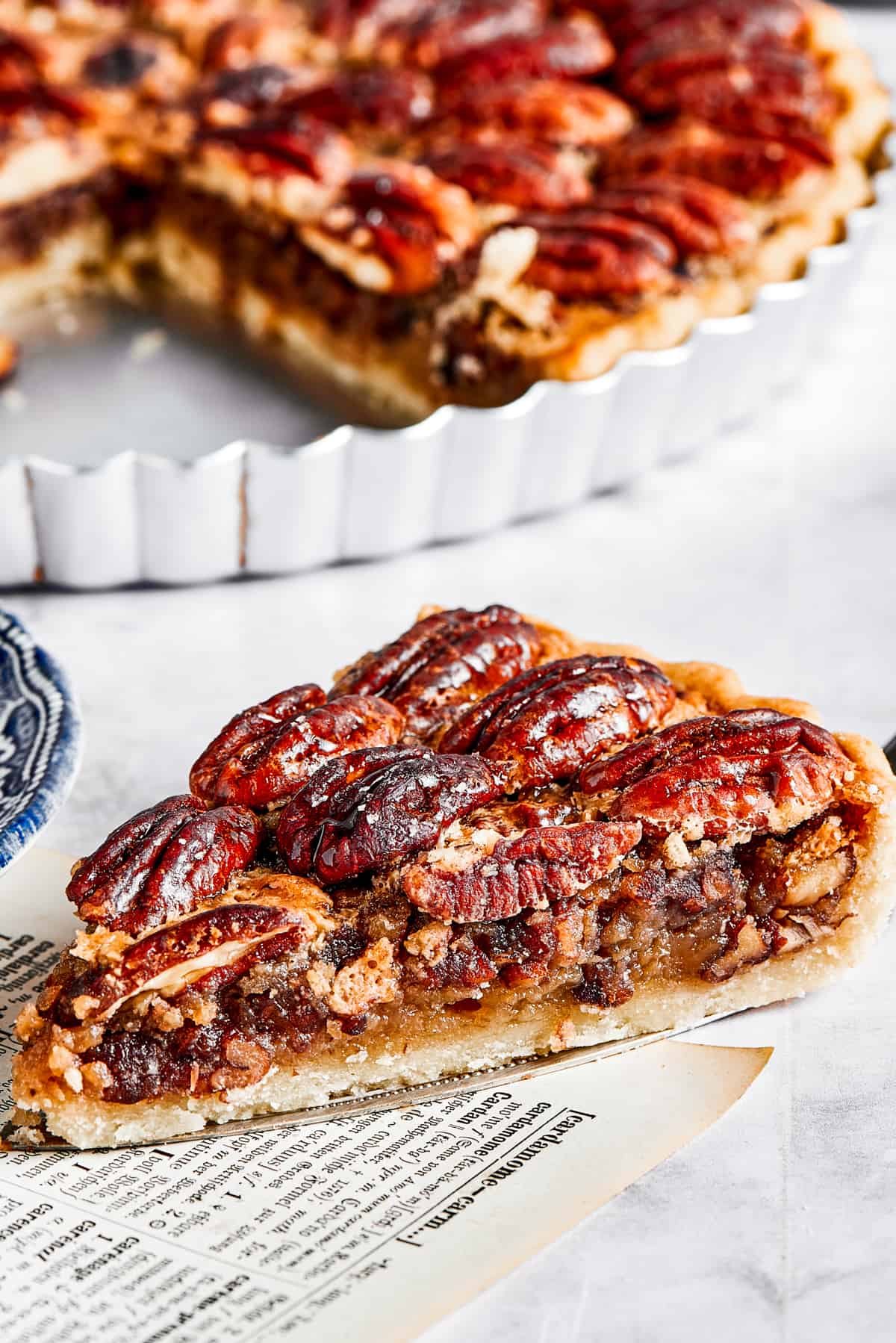 A slice of pie on a pie server, next to the pie dish.