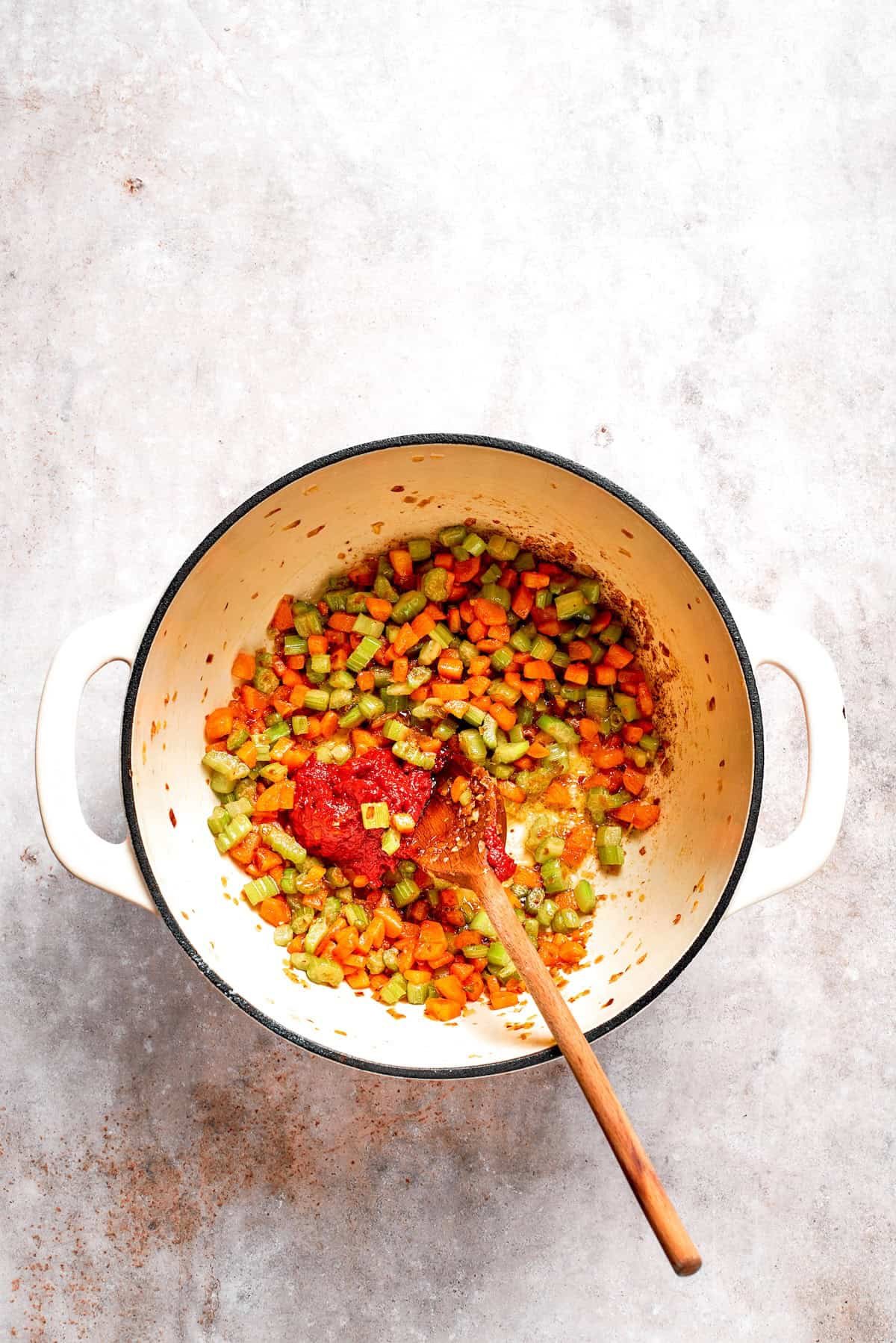 Tomato paste is sauteed with vegetables in a pot.