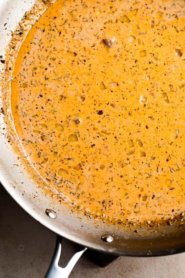 cooking creamy tomato sauce in a stainless steel skillet