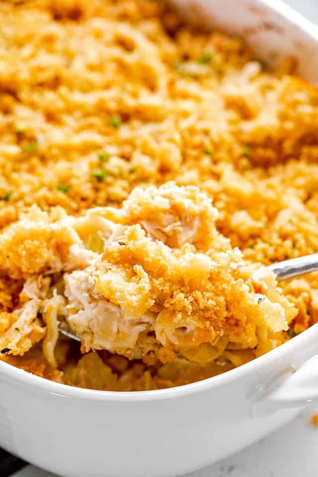 scooping out tuna noodle casserole from baking dish