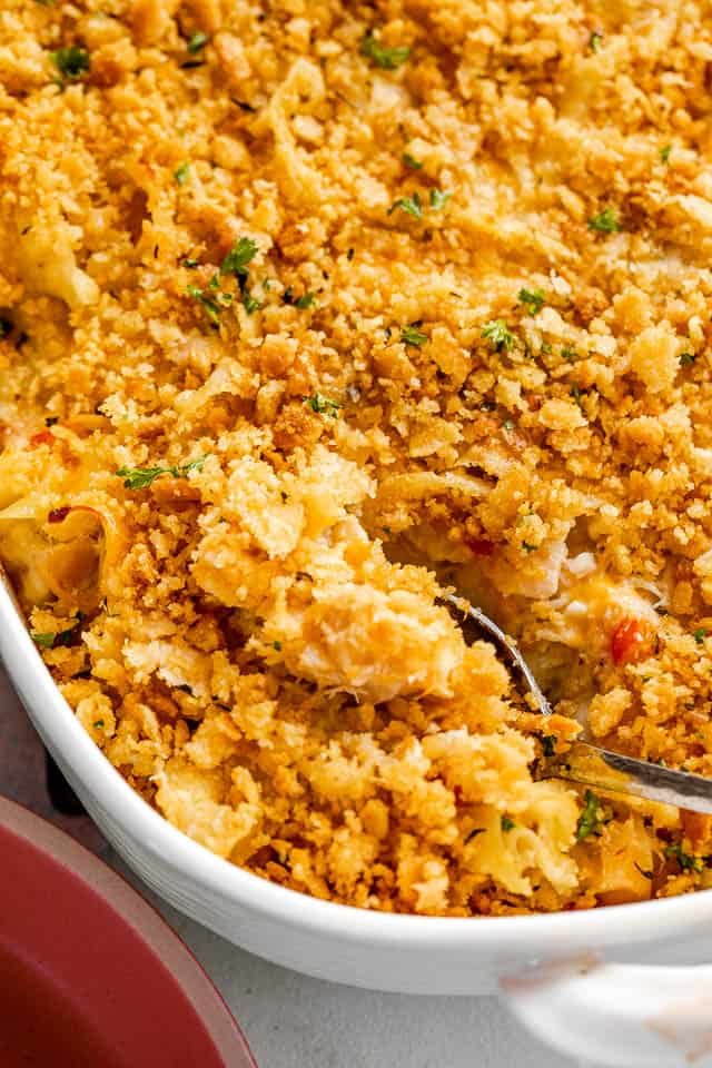 silver spoon cutting into a tuna noodle casserole topped with ritz crackers