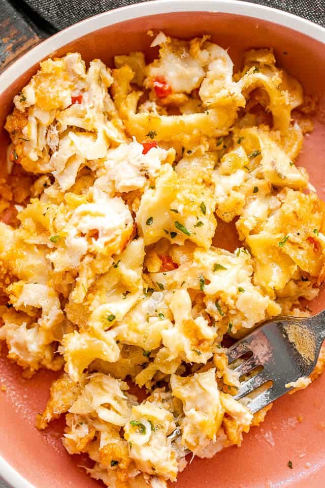 serving tuna noodle casserole in an orange bowl with a silver fork