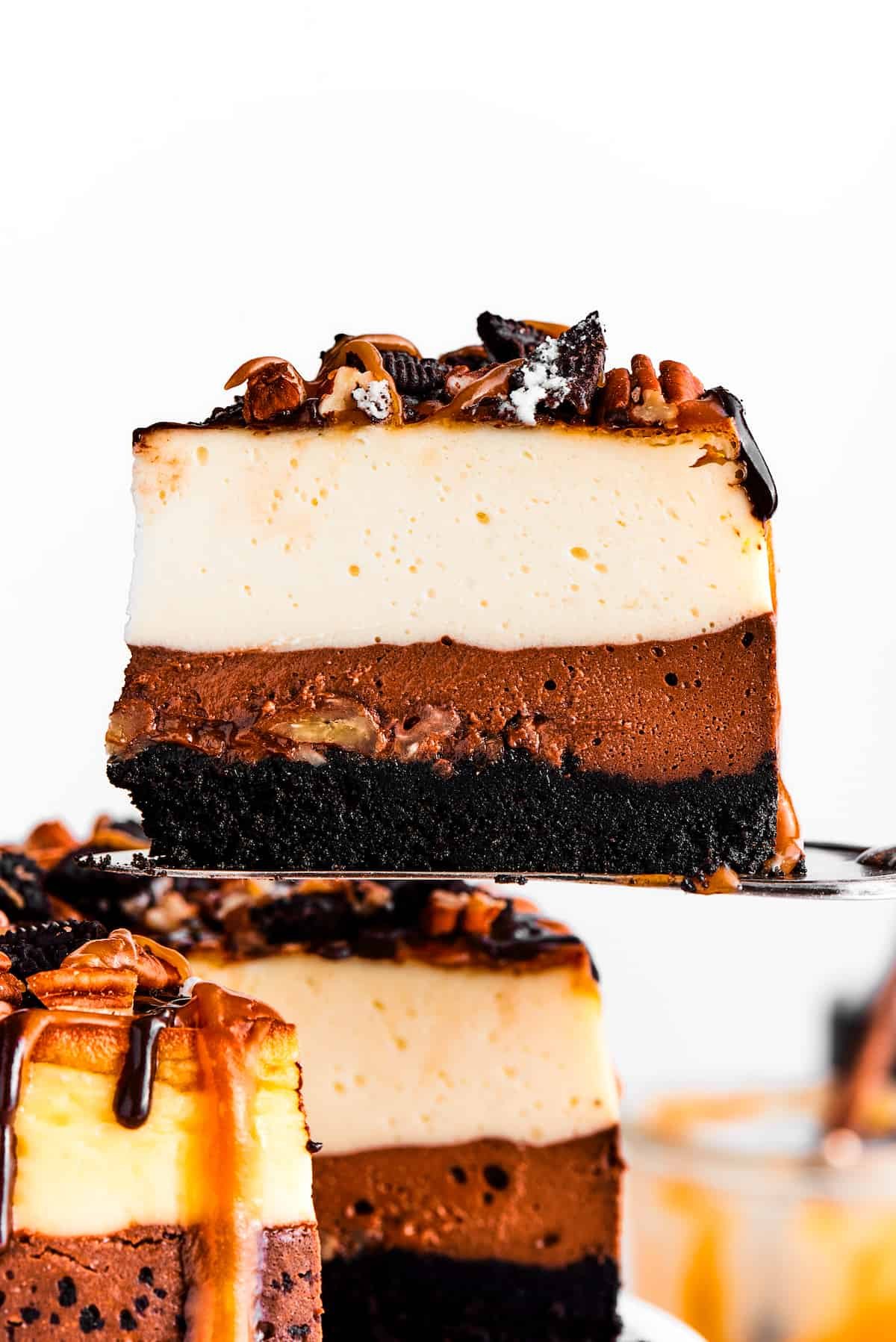 A cake server holding up a slice of turtle cheesecake.