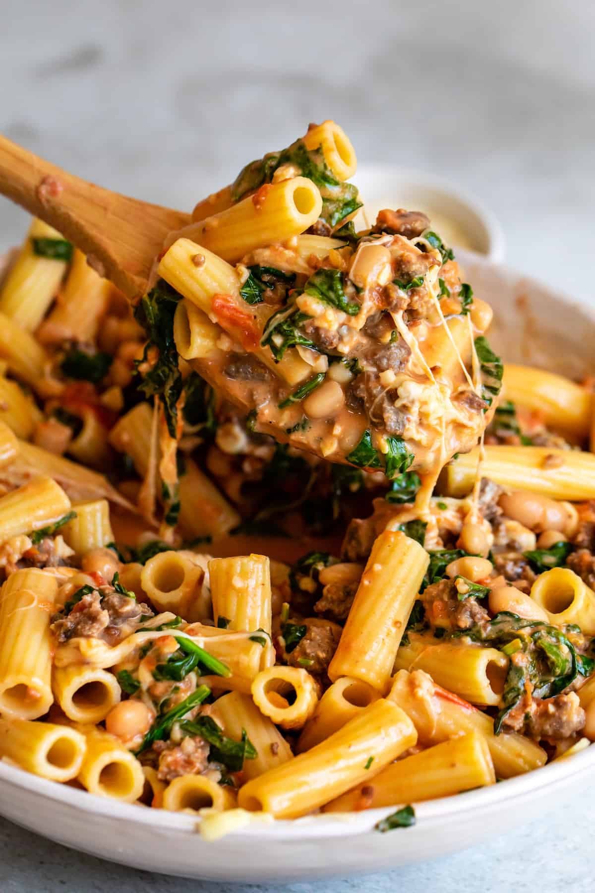 A Heaping Spoonful of Baked Rigatoni Being Scooped Out From a Bowl