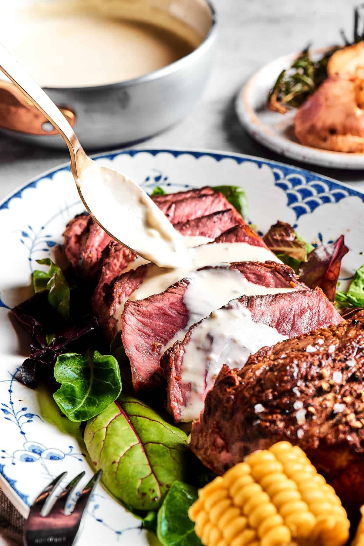 Steak slices with creamy sauce being spooned over the top.