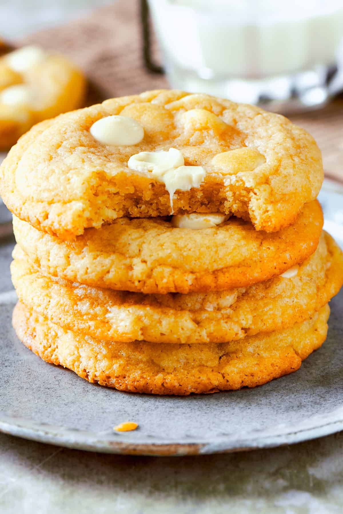 Four stacked up cookies on a plate.