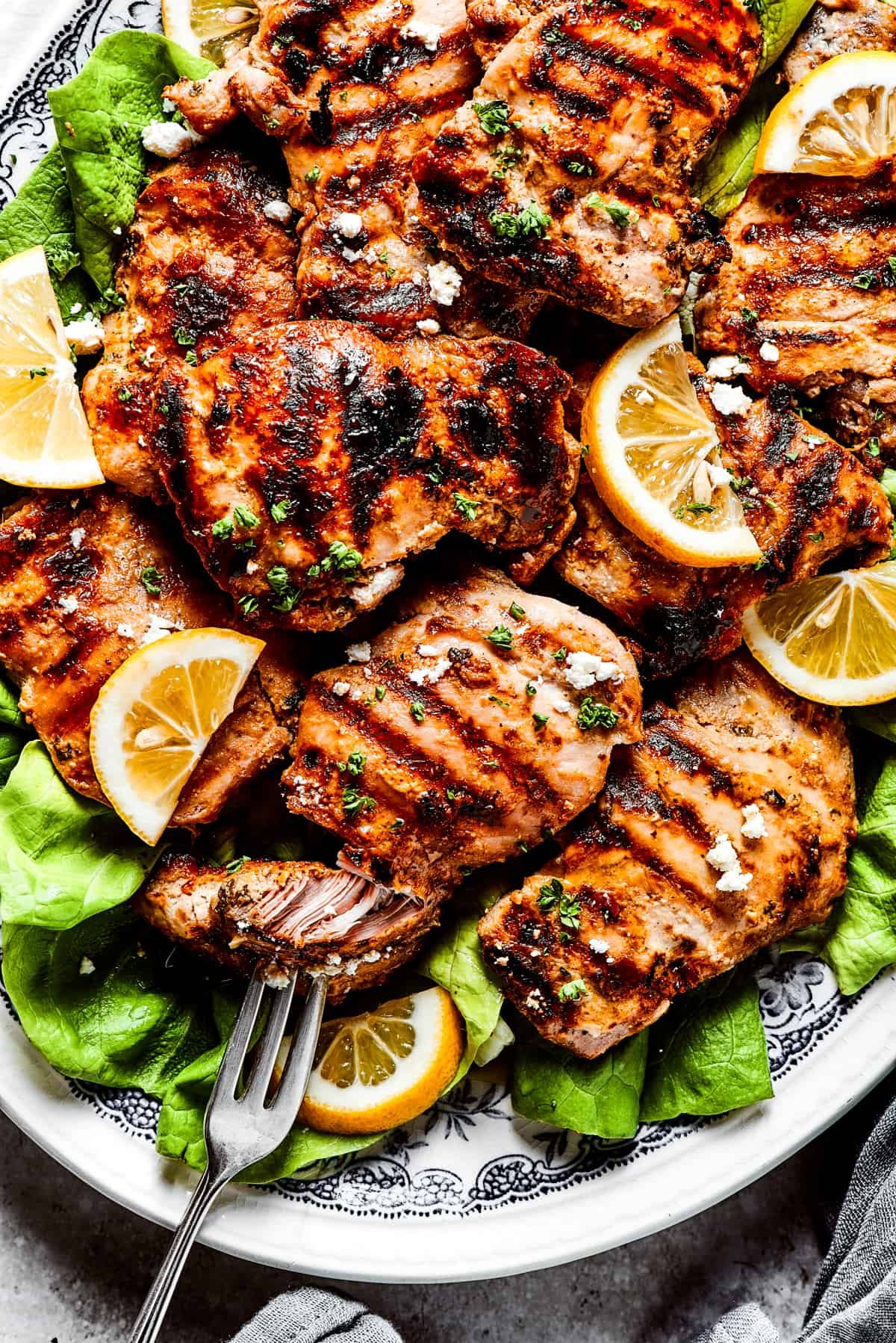 Pulling a piece of grilled chicken apart with a fork.