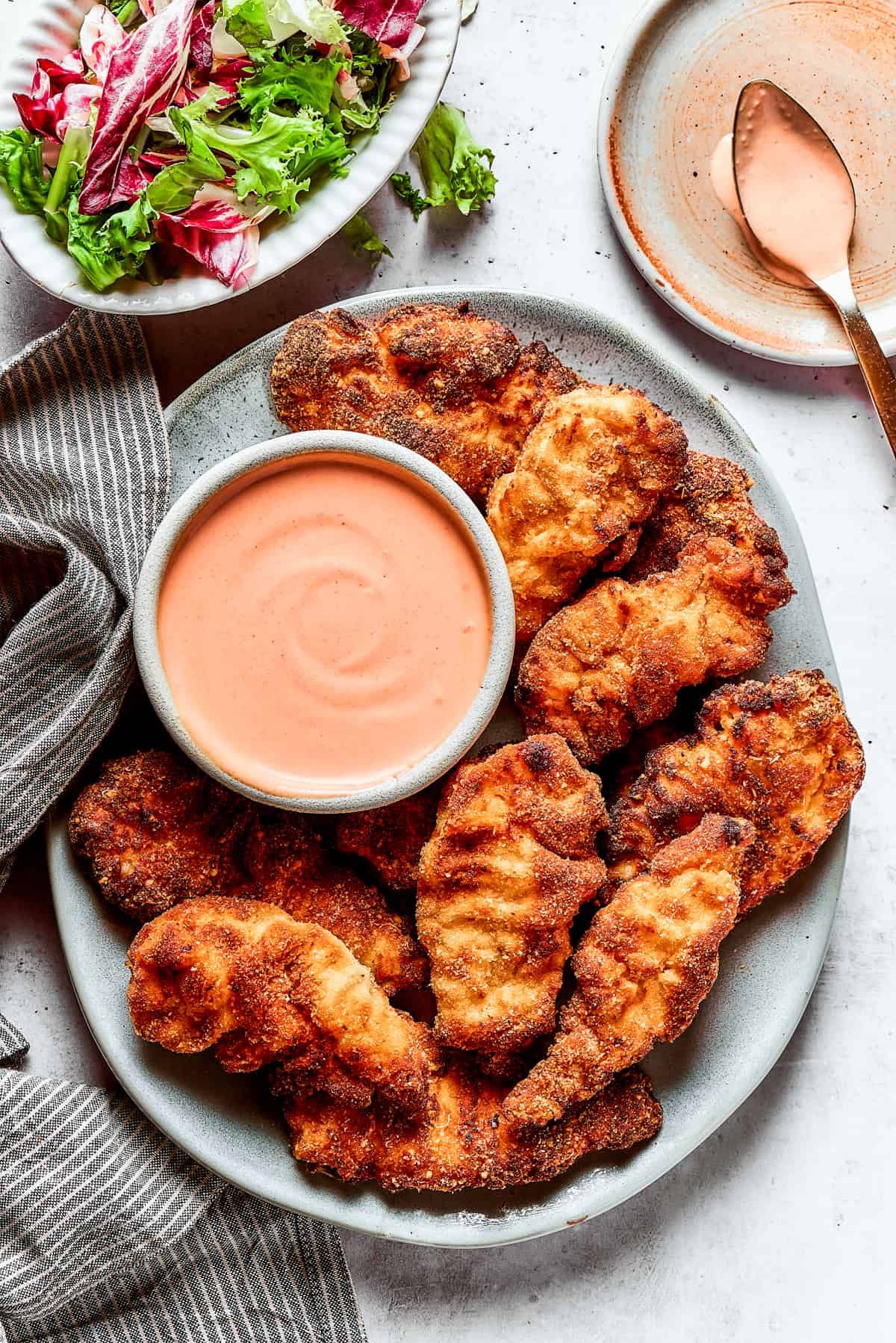 A platter of chicken strips with sauce.