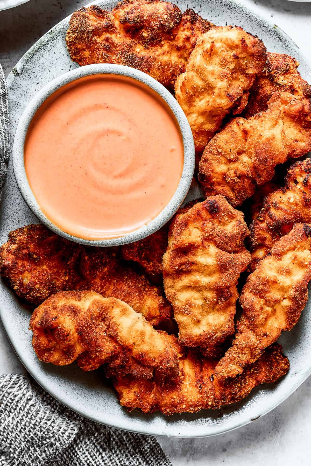 A platter of chicken strips with sauce.