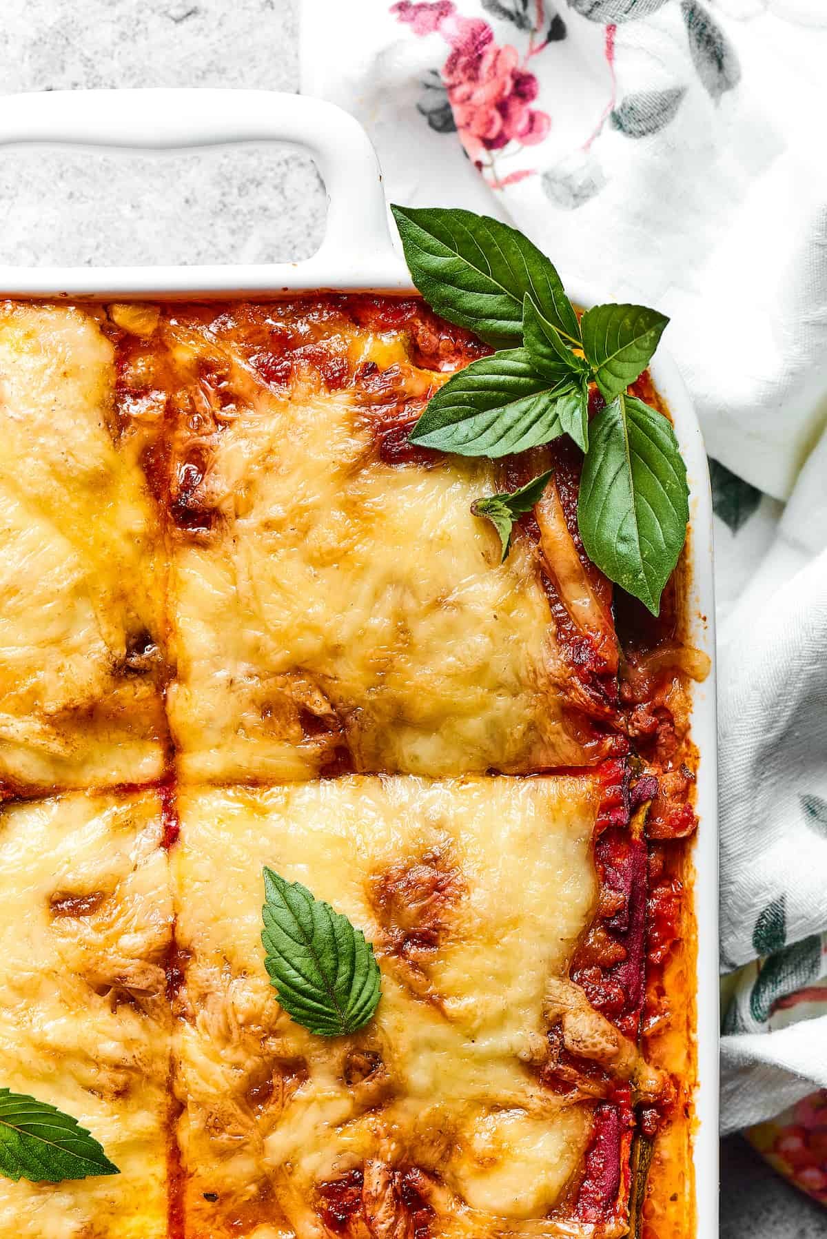 Close-up shot of a corner of zucchini lasagna, garnished with fresh basil.