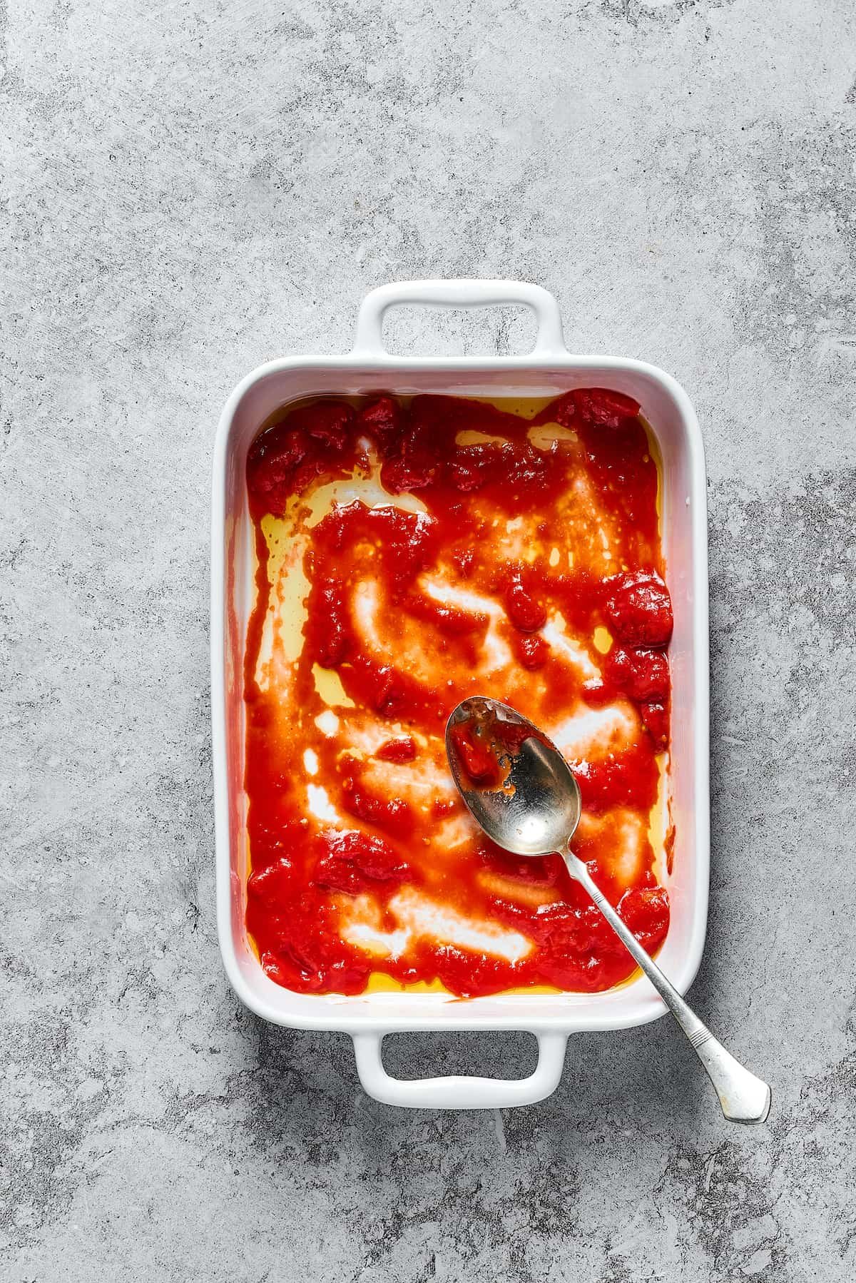 Tomato sauce in the bottom of a baking dish.