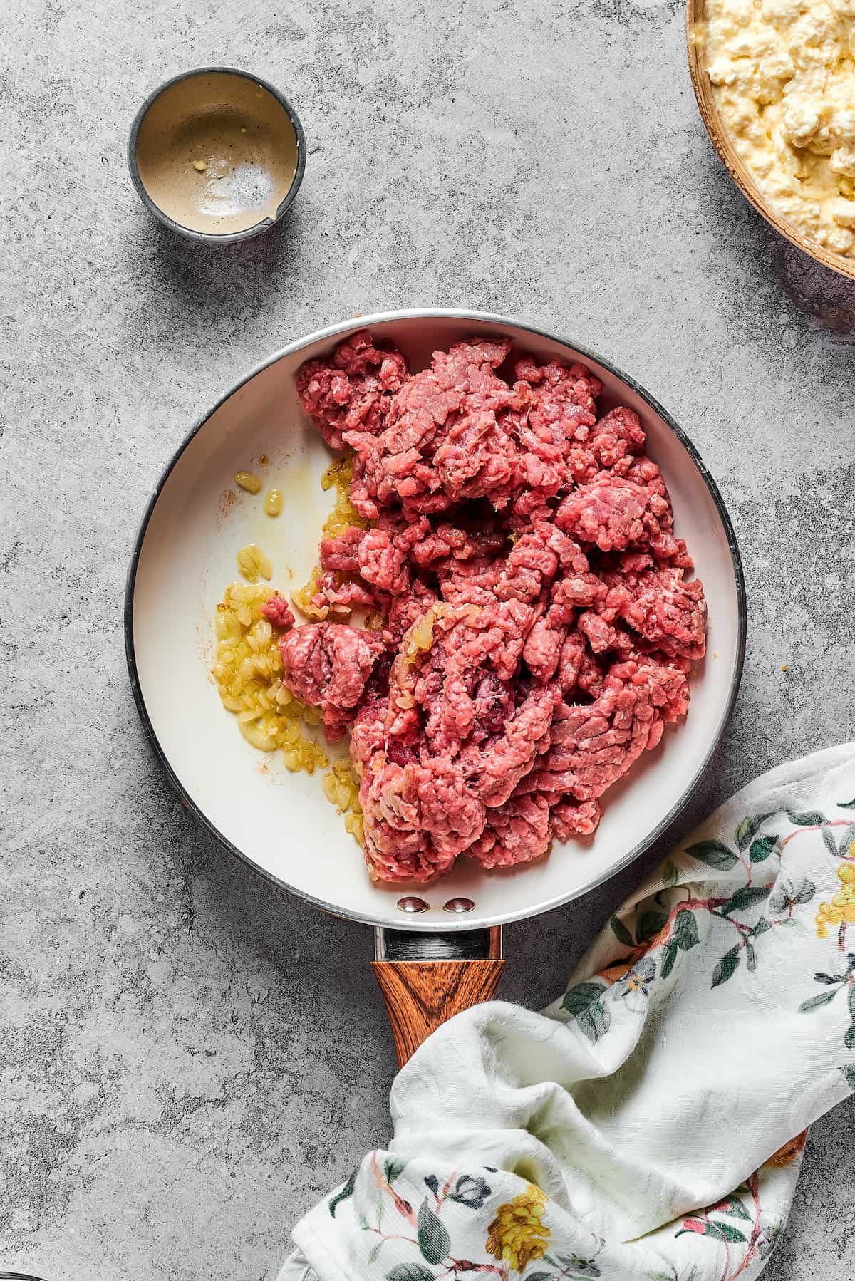 Garlic, onions, and ground beef cooking in a skillet.