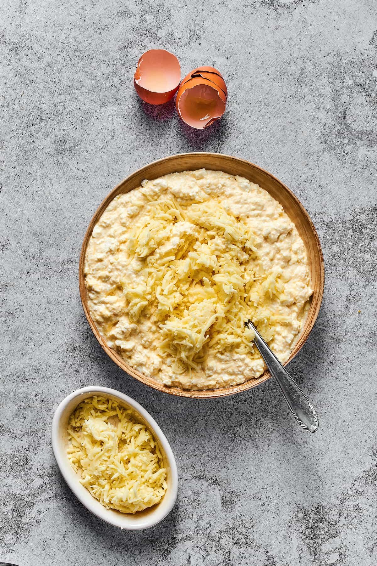 Shredded mozzarella added to a large bowl of cheese filling mixture.