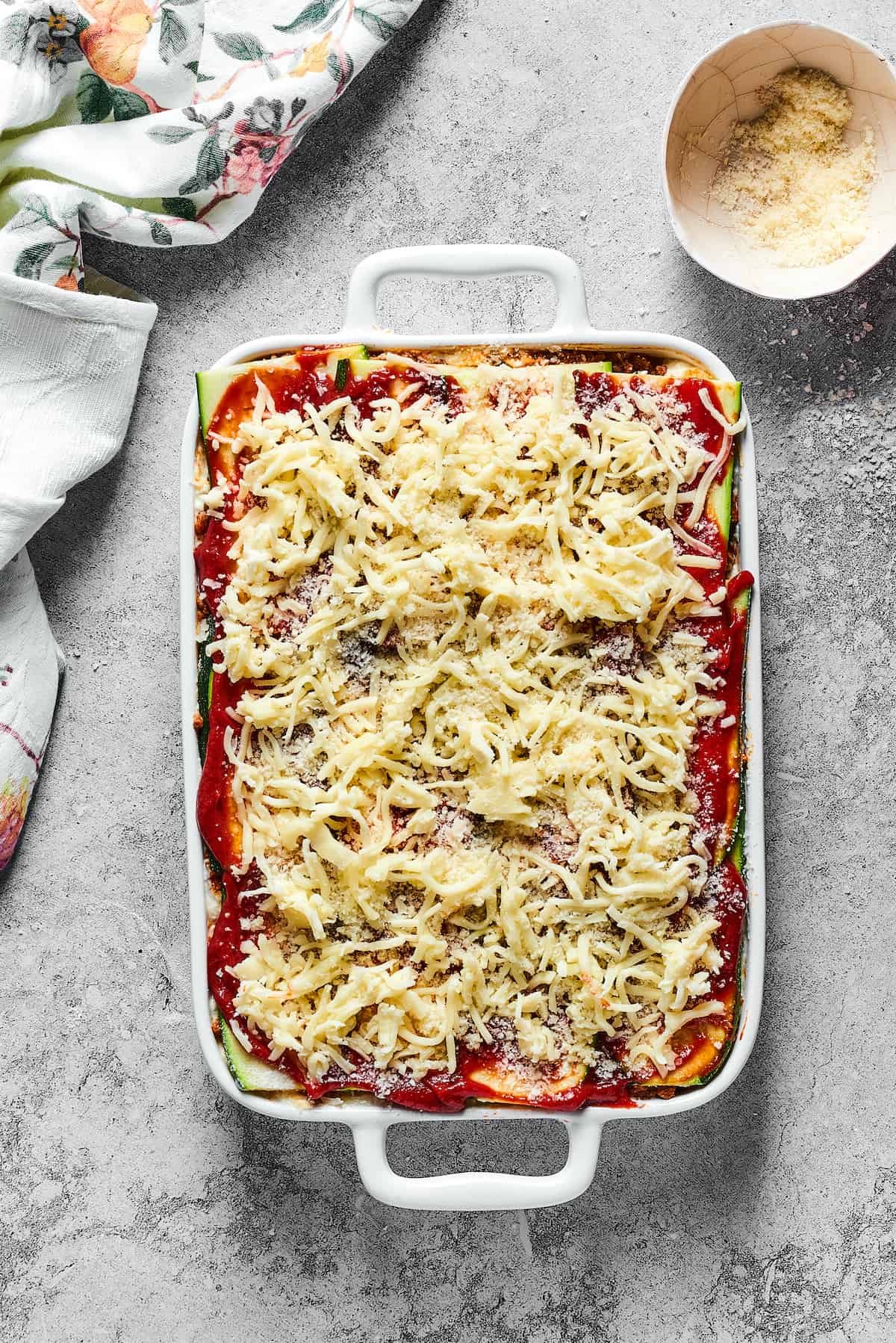 Mozzarella sprinkled on top of an unbaked lasagna.