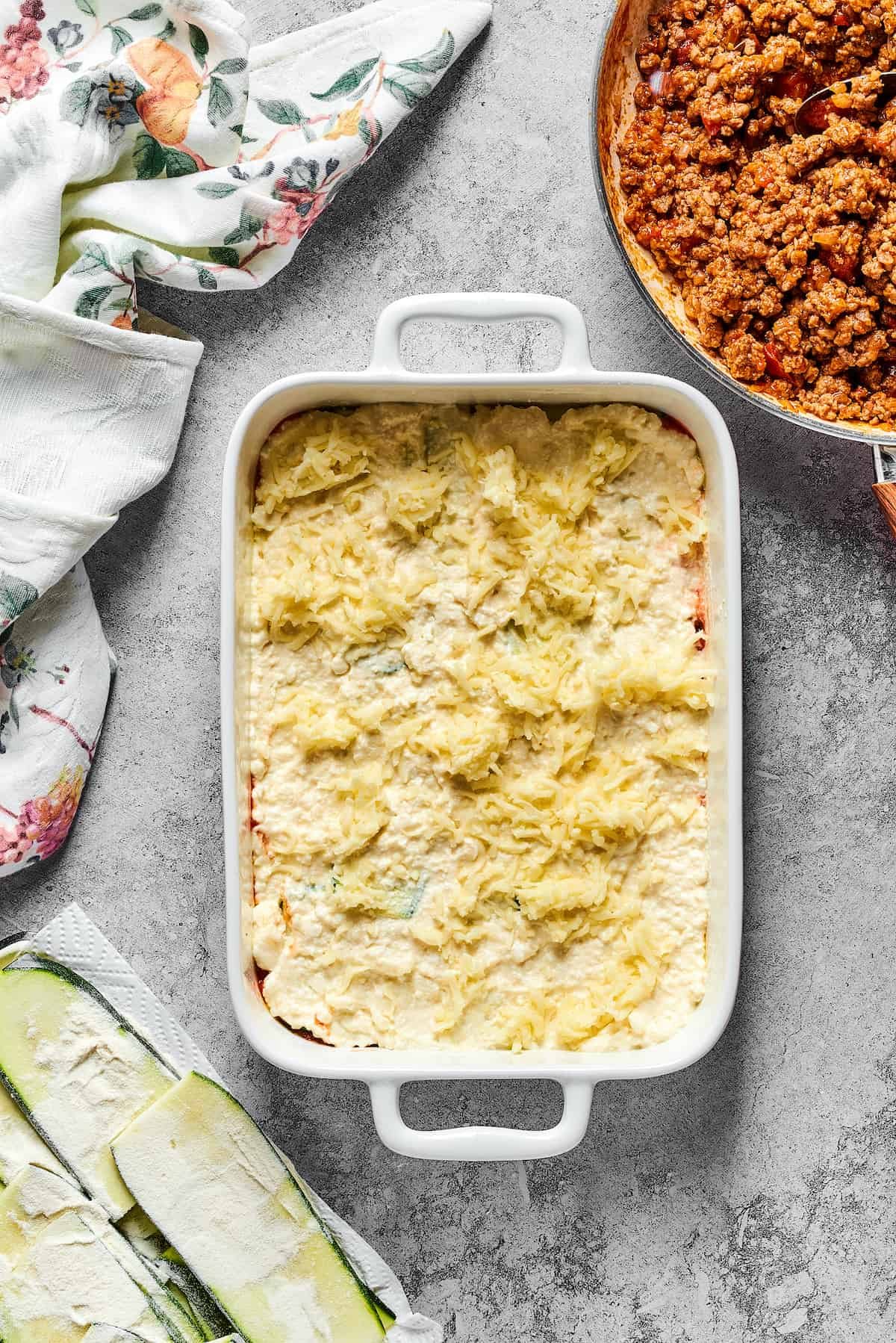Mozzarella sprinkled over other lasagna layers in a baking dish.